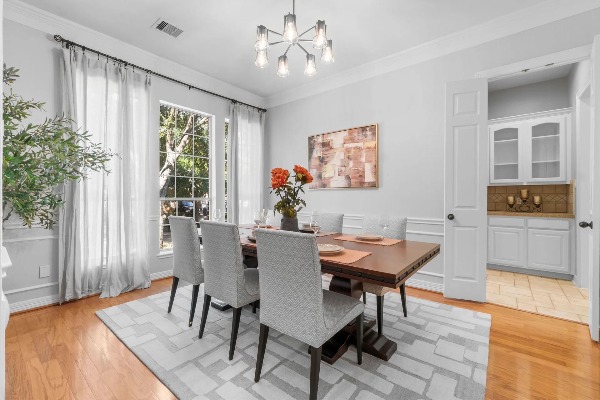 Dining room with crown and wainscot molding, hardwood floors, and soft lighting