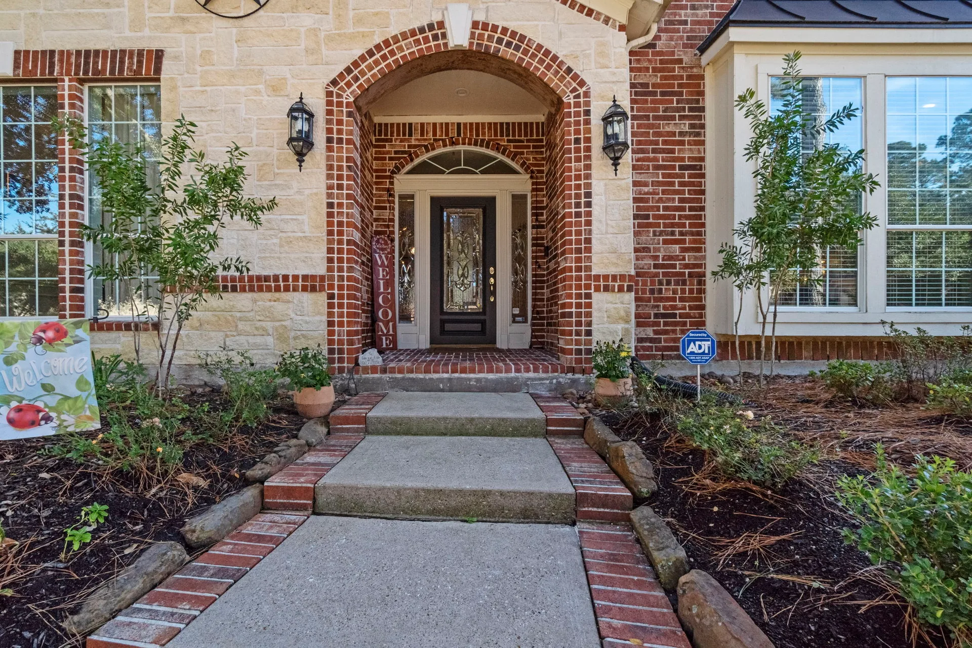 Front entryway with light stone and red brick detailing, concrete walkway