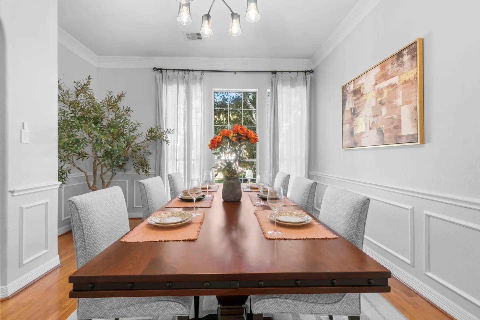 Dining room with wainscoting, hardwood floors, sputnik light fixture, and natural light