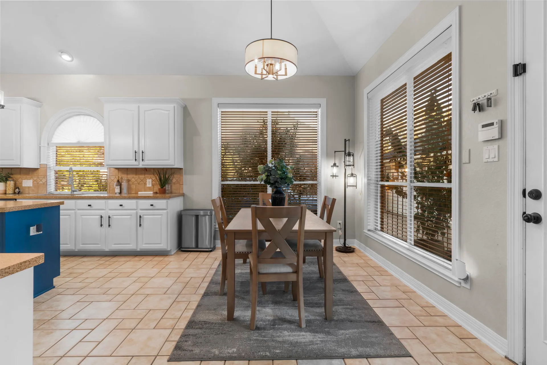 Dining area adjacent to kitchen with tile floors and blue lower cabinets