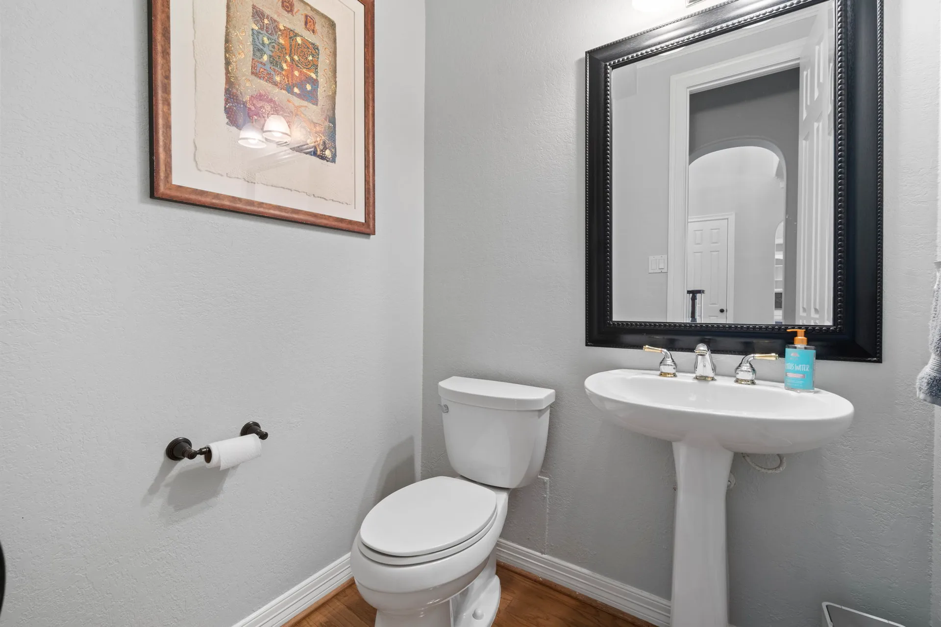 Powder room with white pedestal sink and black framed wall mirror