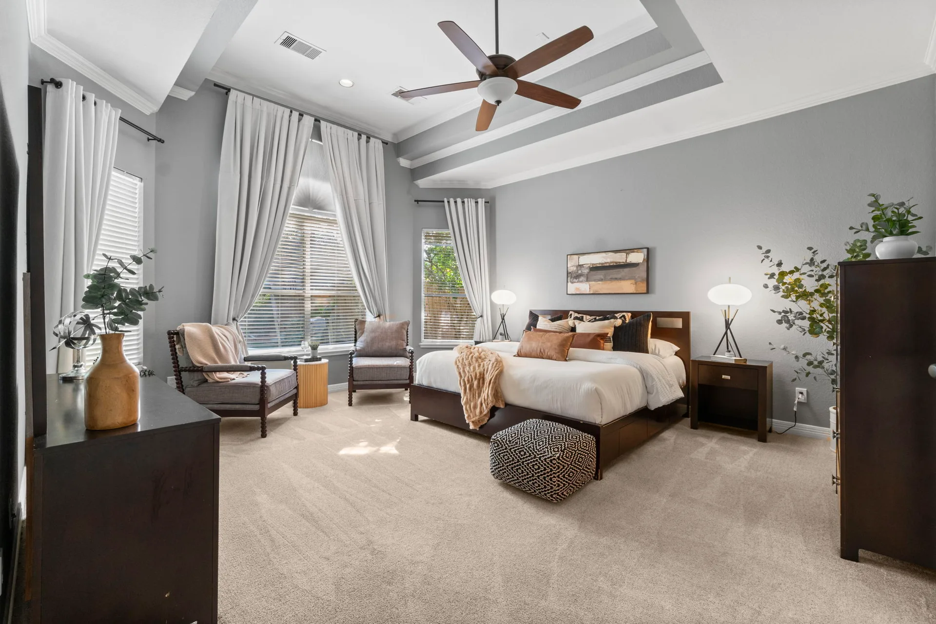 Primary bedroom suite with tray ceiling and natural light