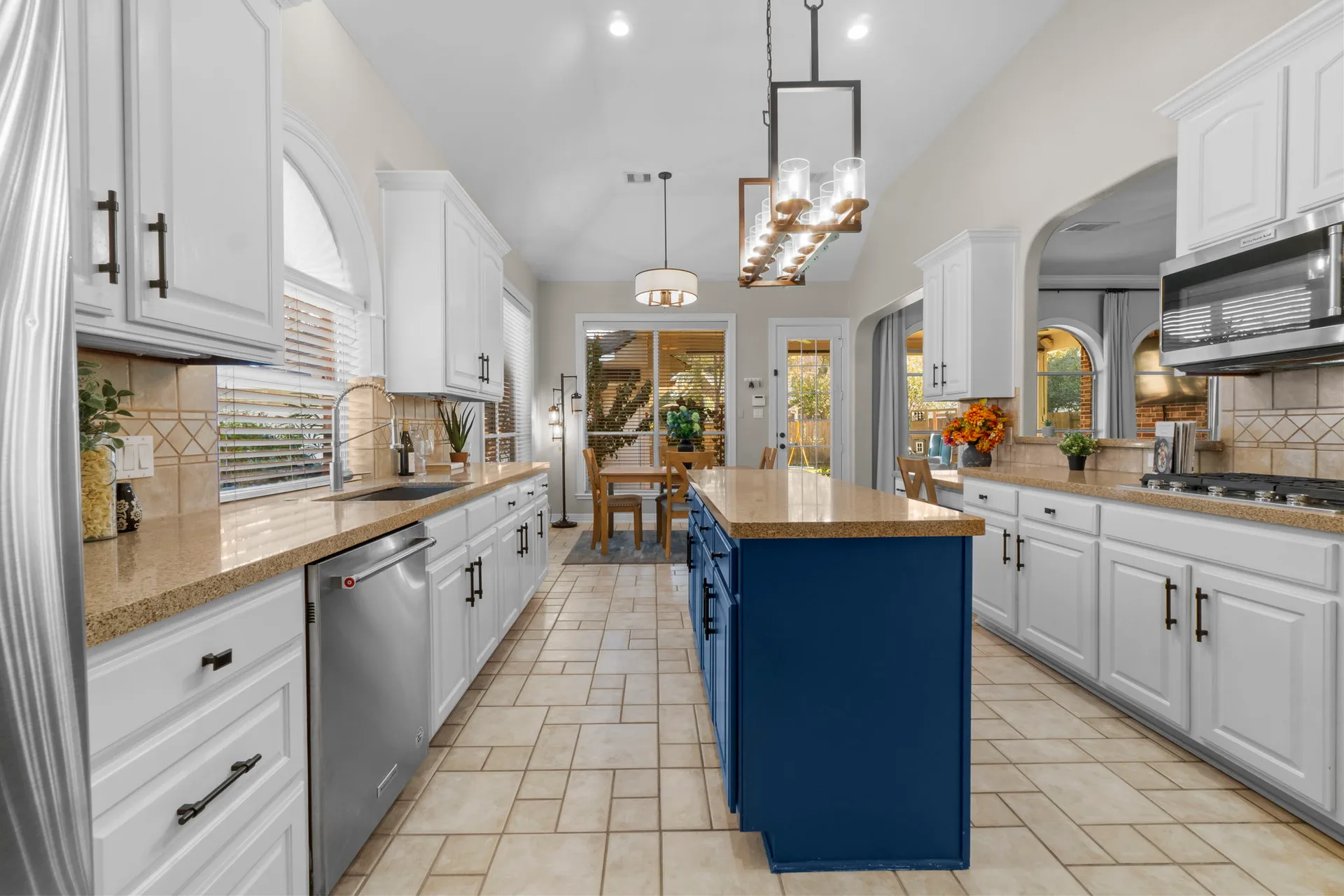 Kitchen with white cabinetry and navy blue island with granite countertops