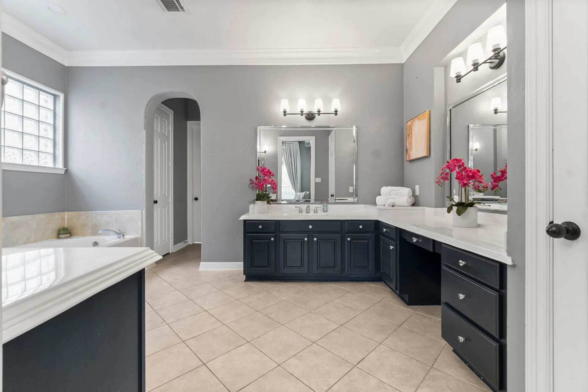 Primary bathroom with navy vanity cabinetry, white stone countertops, and tile flooring