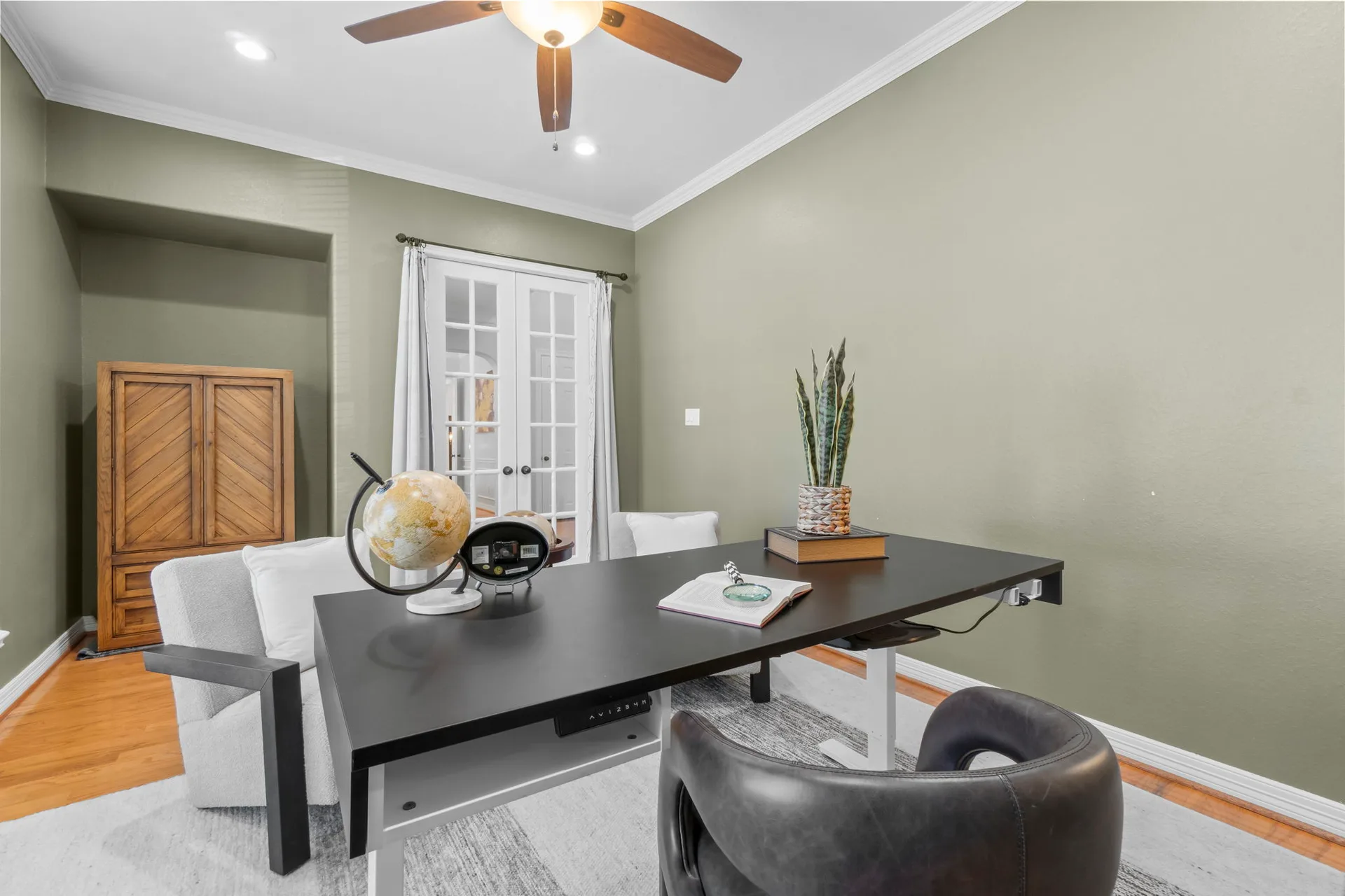 Home office with olive-green walls, light wood flooring, and French doors