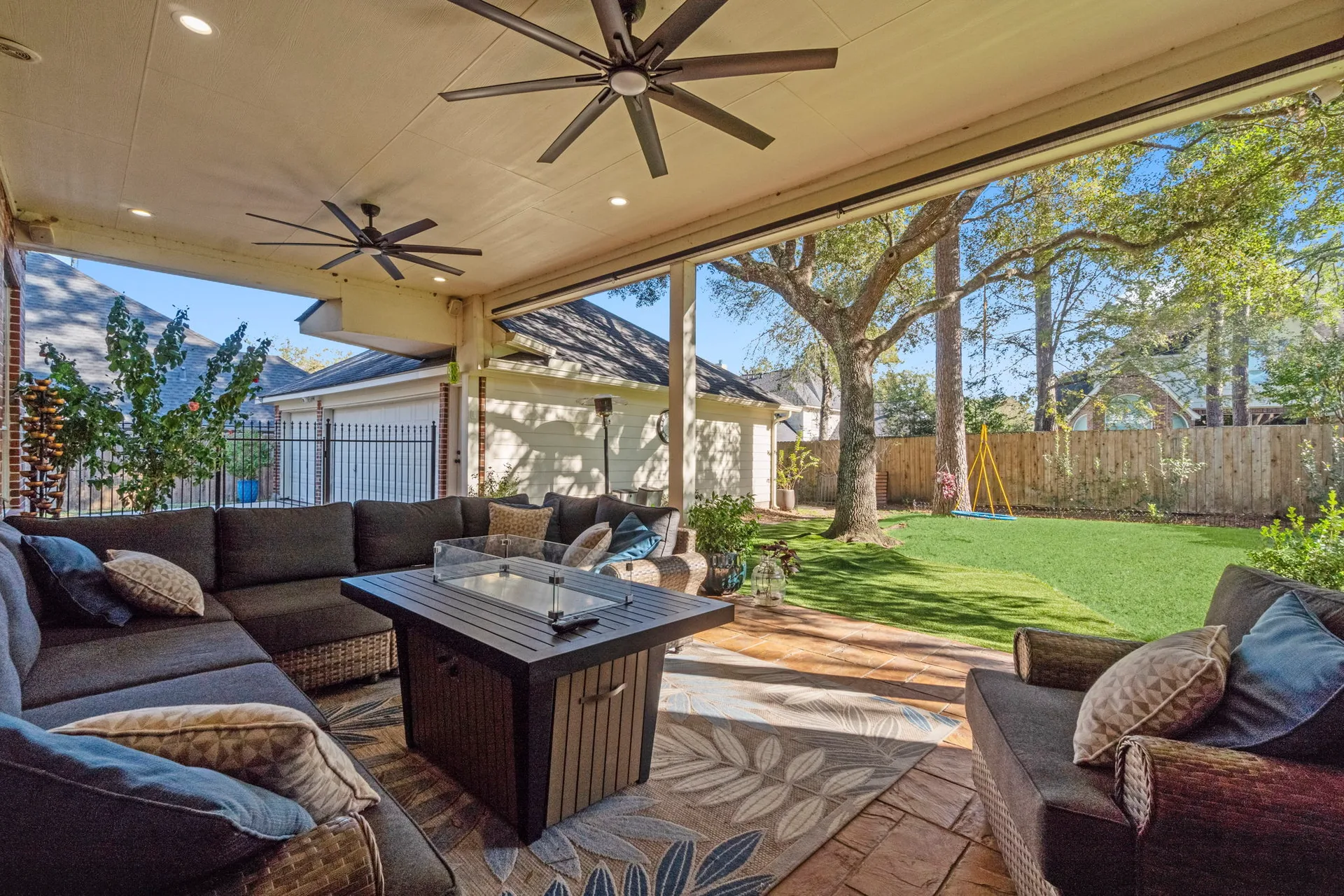 Covered back patio at 6110 Peachtree Hill Court with seating, ceiling fans, and fenced backyard