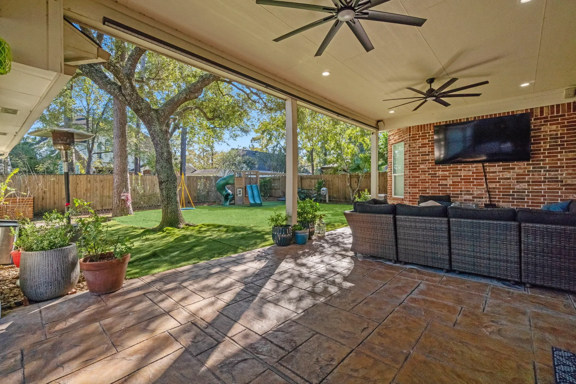 Covered backyard patio with flagstone concrete flooring and ceiling fans