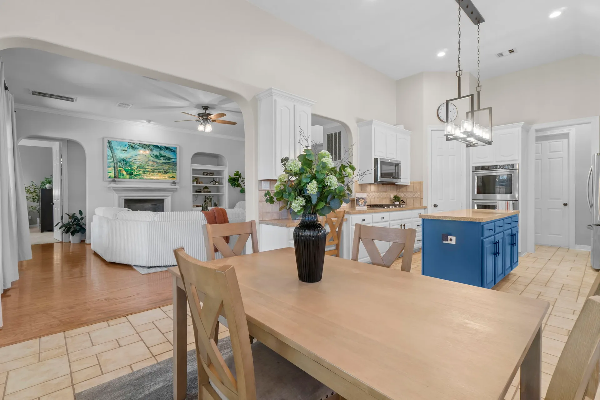Open concept kitchen and dining area with white shaker cabinets and blue island