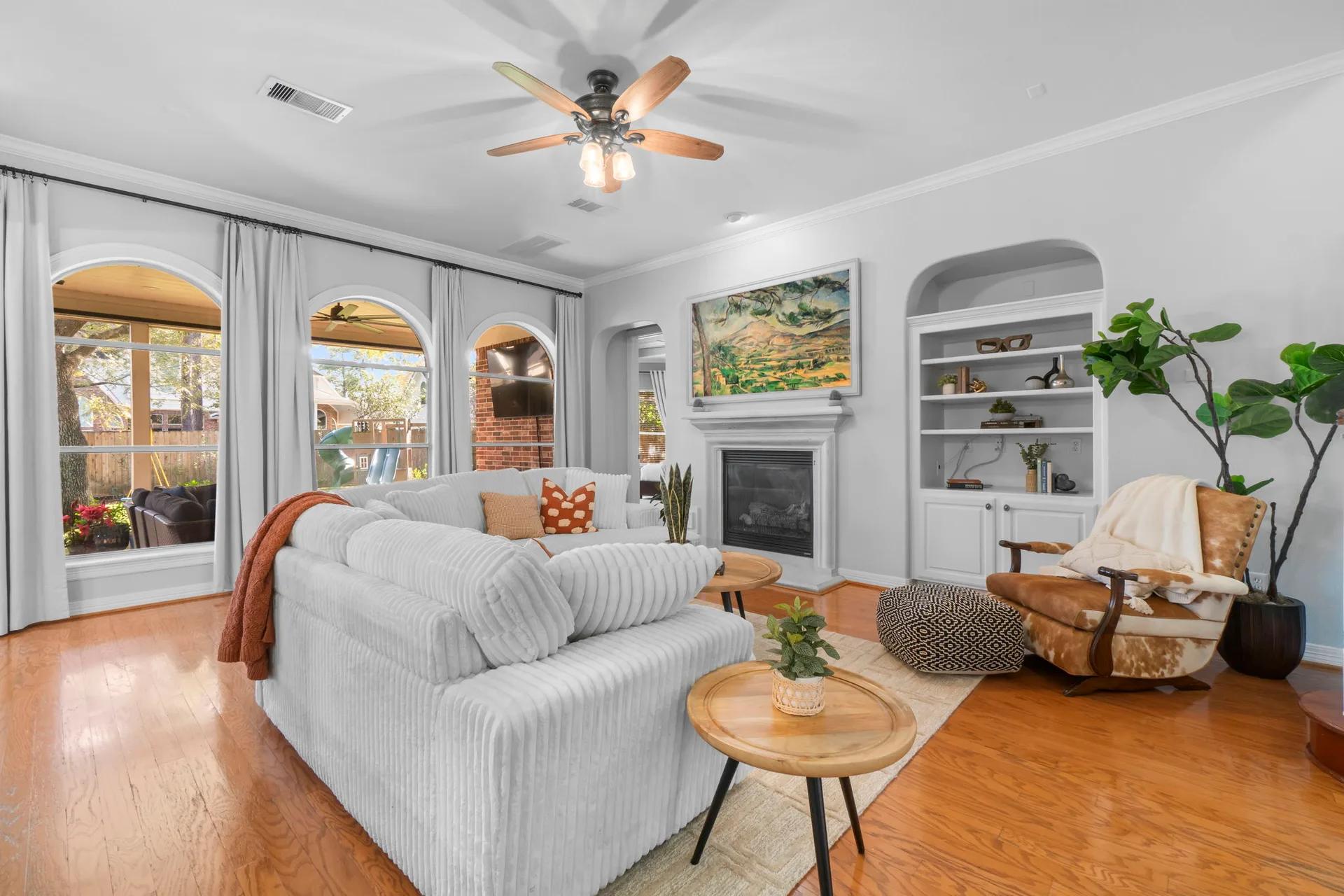 Living room with fireplace, white mantel, built-in shelving, and hardwood floors