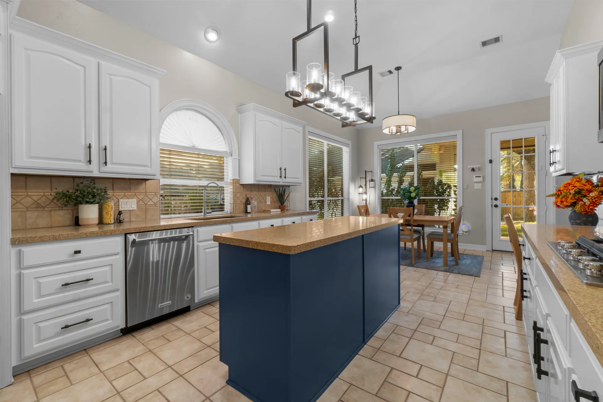 Kitchen and dining nook with white cabinetry, blue island, and tile flooring