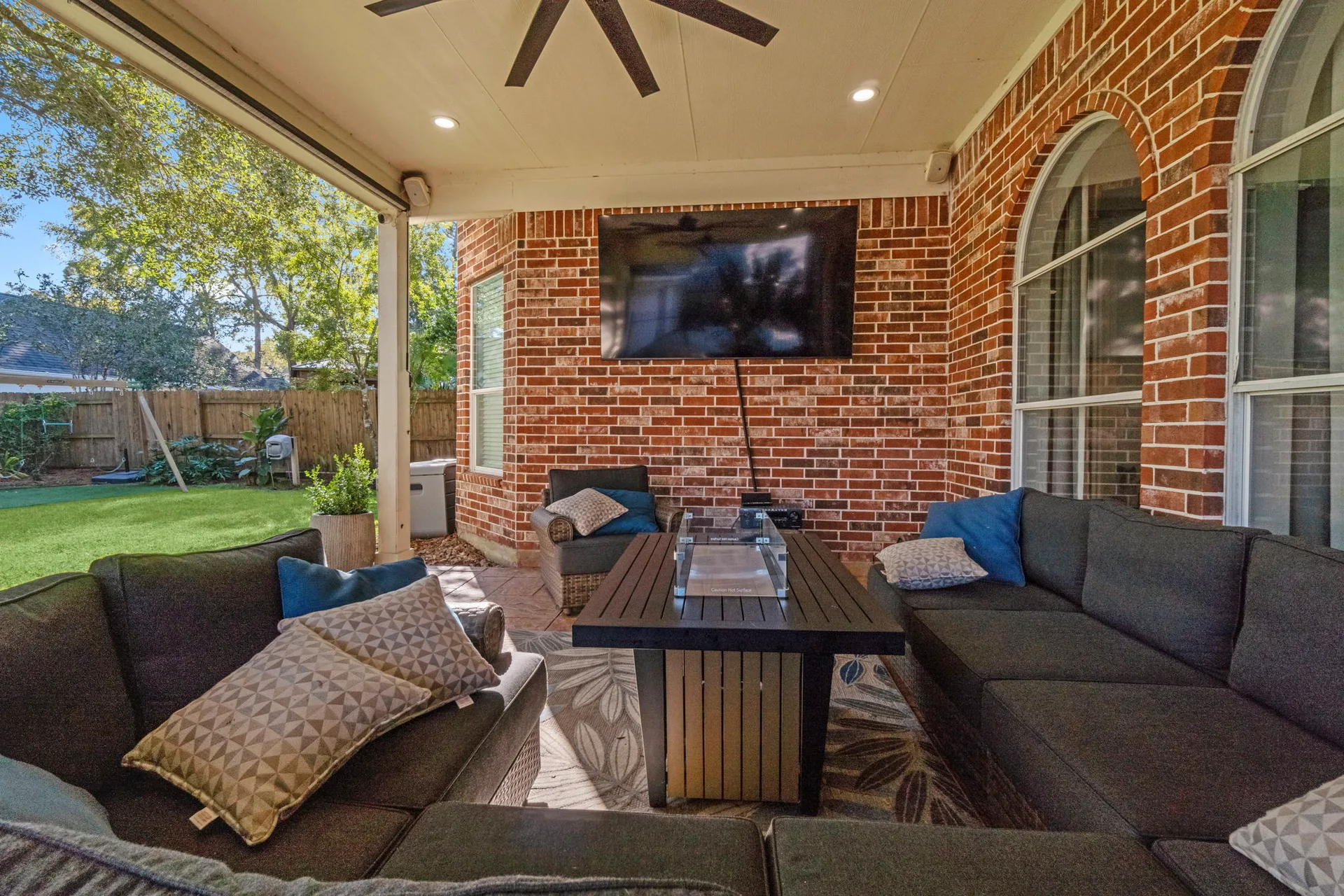 Outdoor patio living space with red brick wall, covered ceiling, and tiled flooring