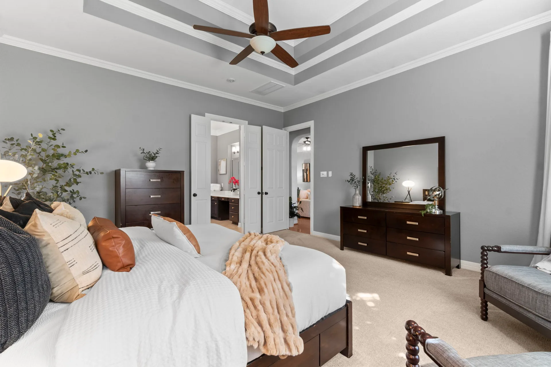 Primary bedroom with tray ceiling, natural daylight, and grey walls