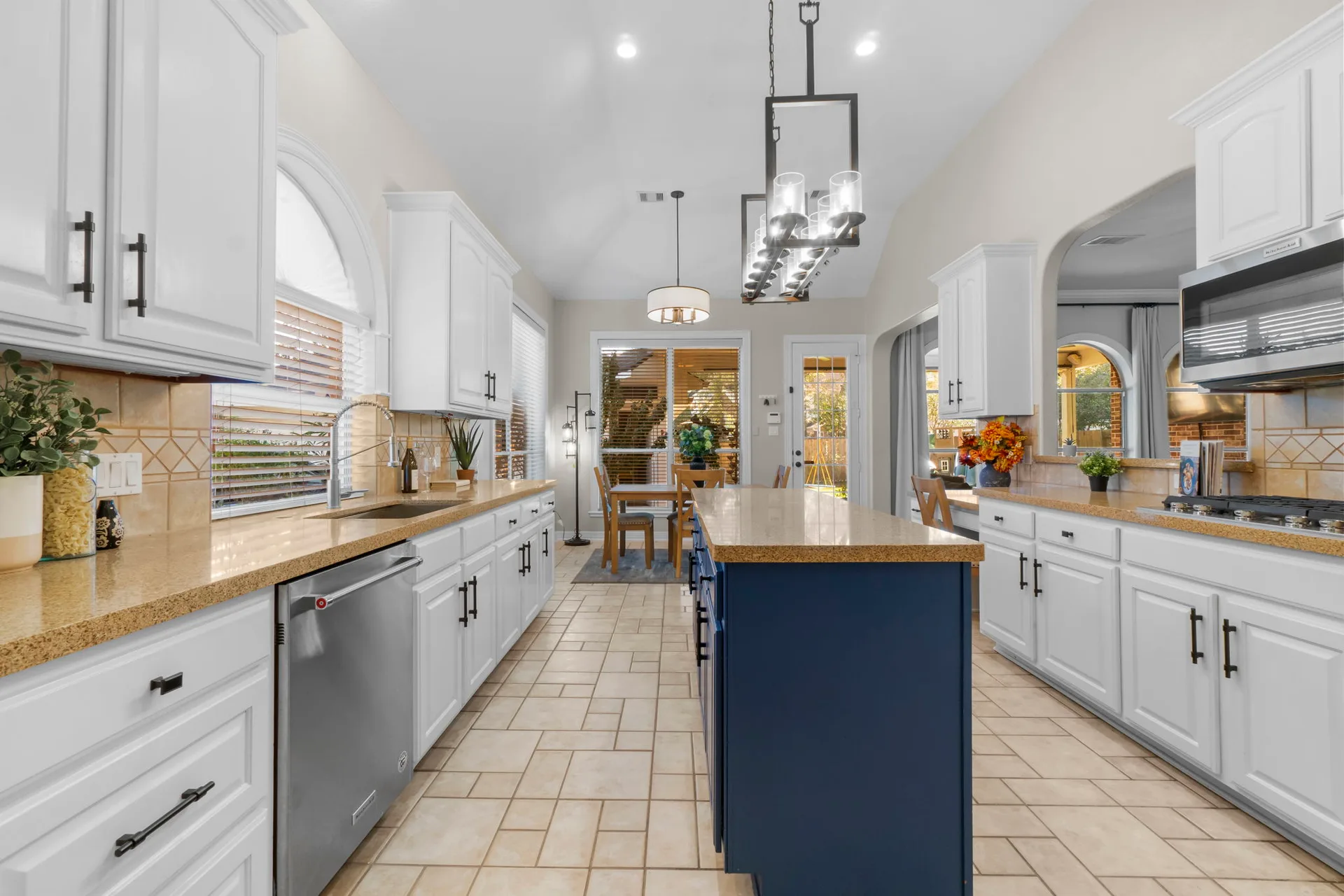 Kitchen with white perimeter cabinets, navy blue island, and granite countertops