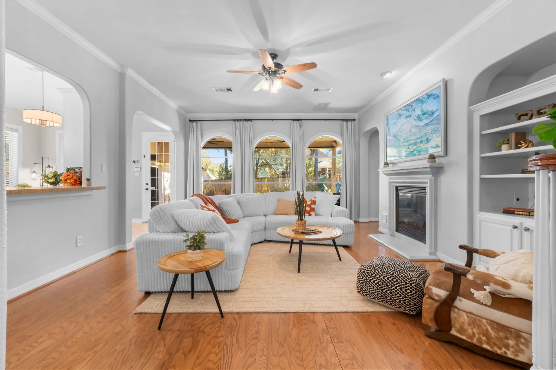 Living room with arched windows, fireplace, built-in shelving, and natural daylight