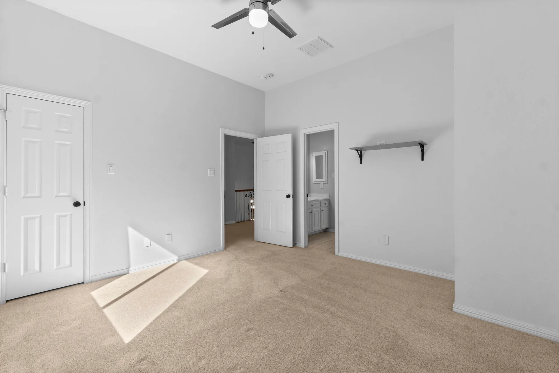 Bedroom with beige carpeting, white walls, and natural lighting
