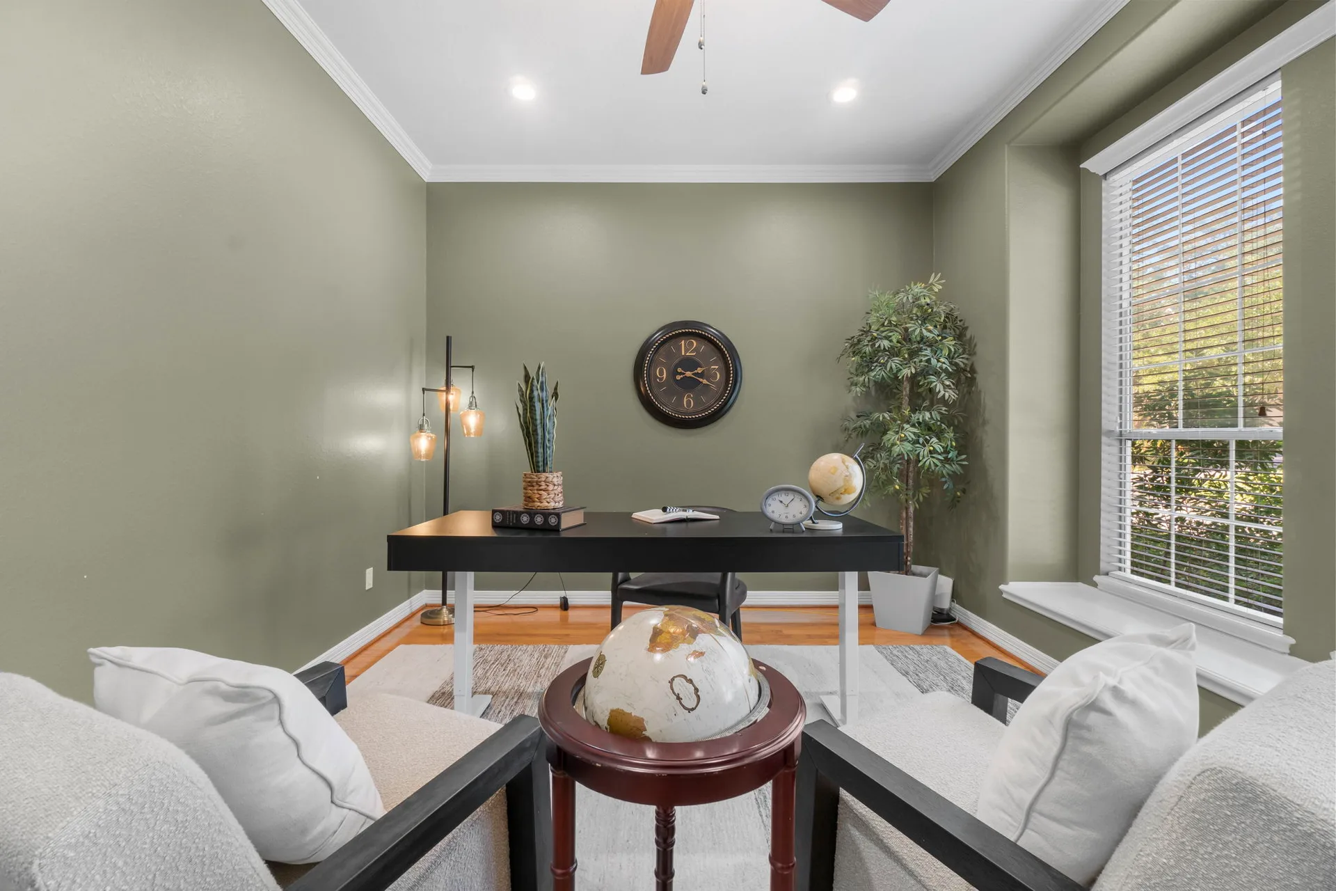 Office with sage green walls, white trim, hardwood floors, and natural light from window