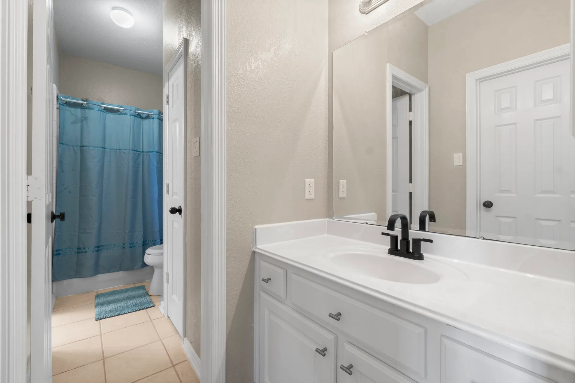 Bathroom showing vanity and bath/shower combo with white vanity and beige tile flooring