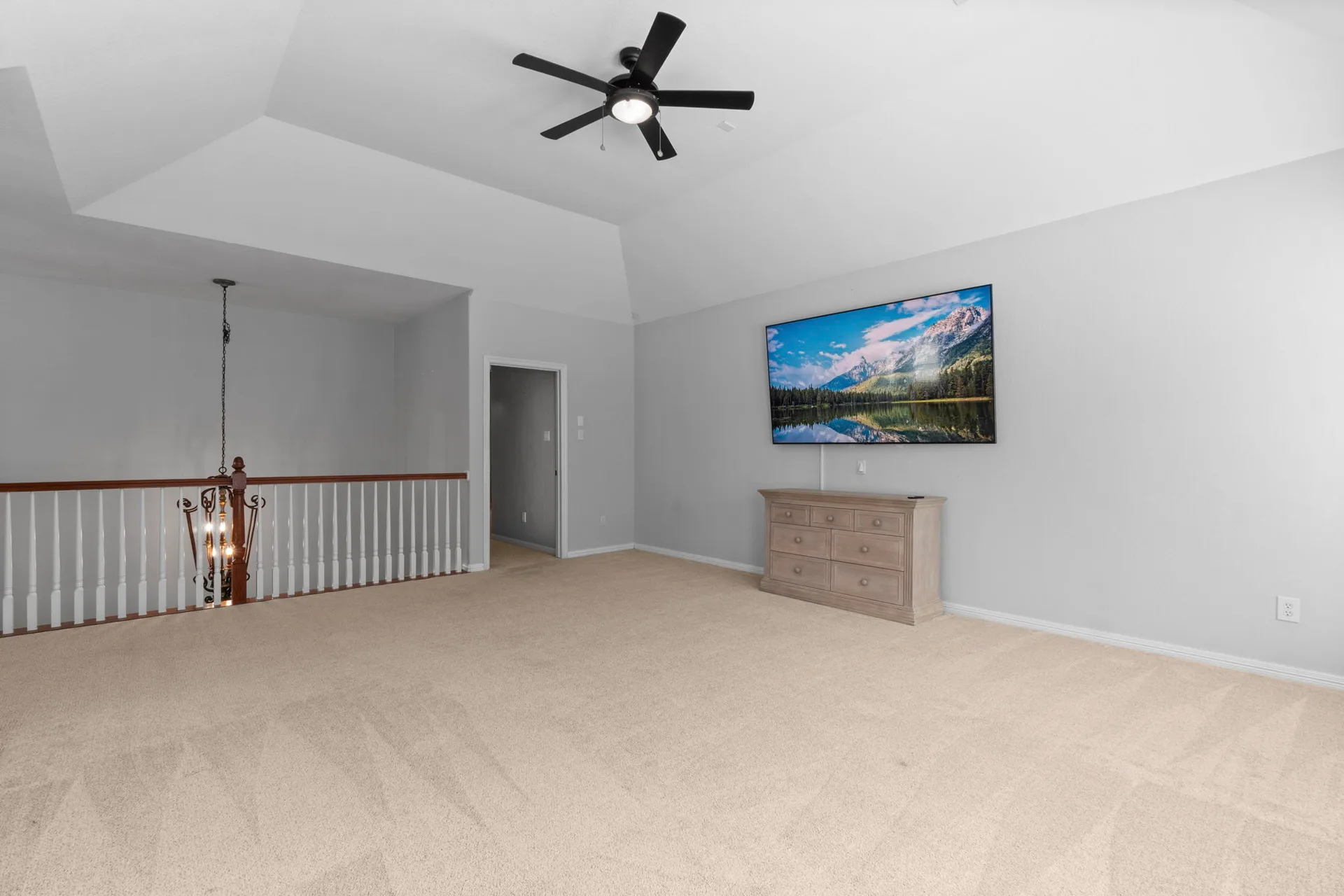 Upstairs loft or bonus room with vaulted tray ceilings and railed landing