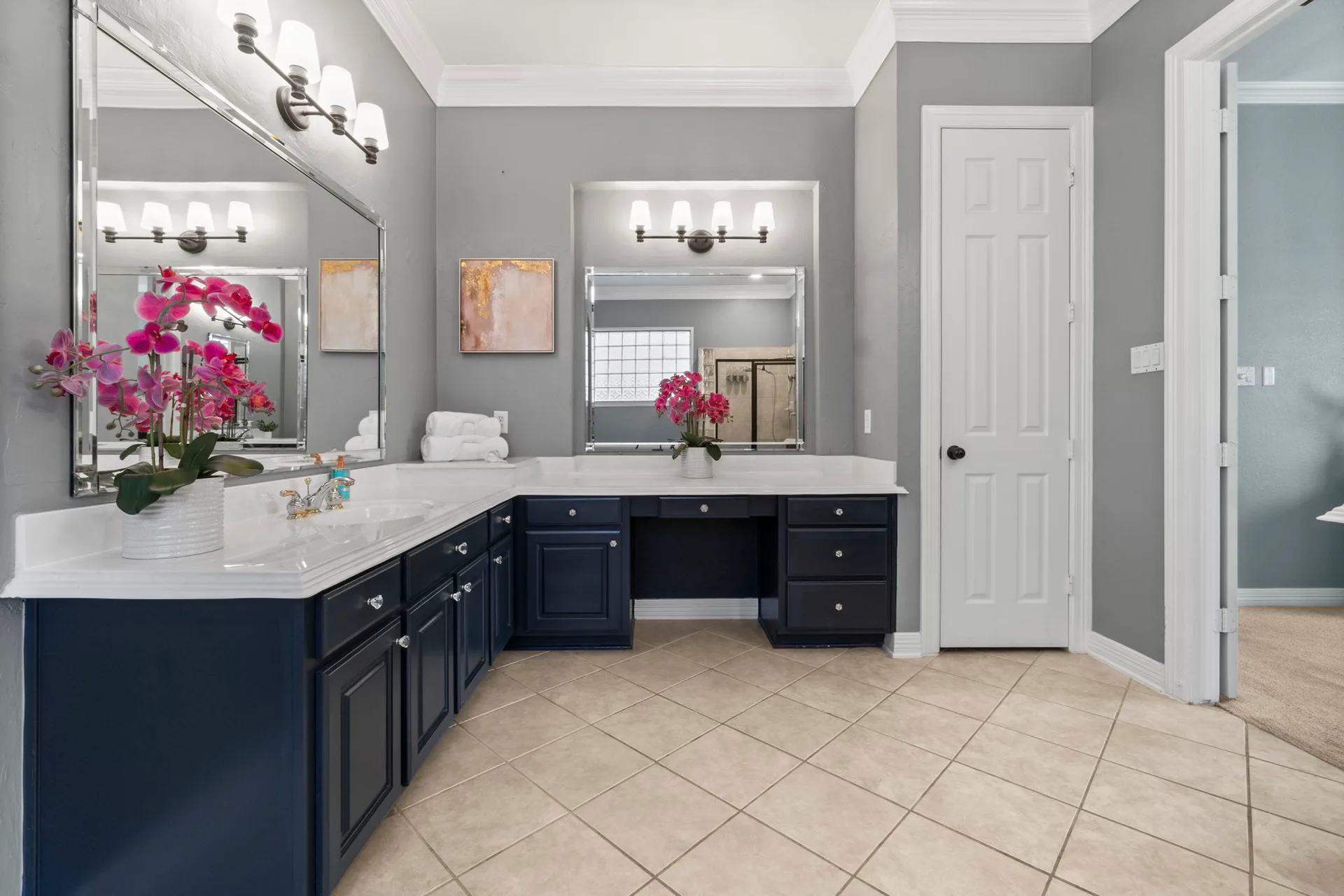 Bathroom vanity with dark navy cabinetry, white countertop, and three vanity light fixtures