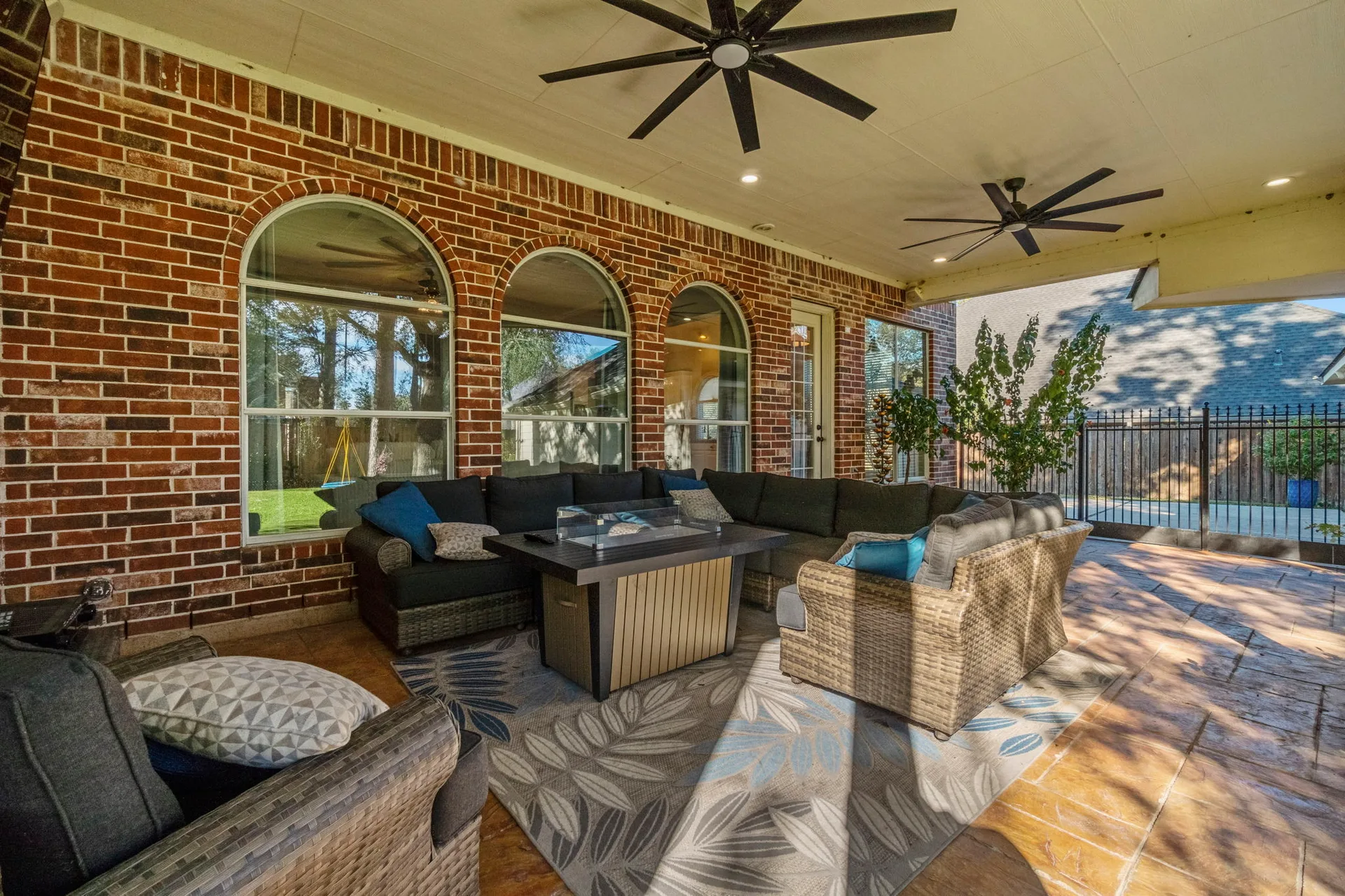 Covered patio with vaulted ceiling, arched windows, and outdoor living furniture