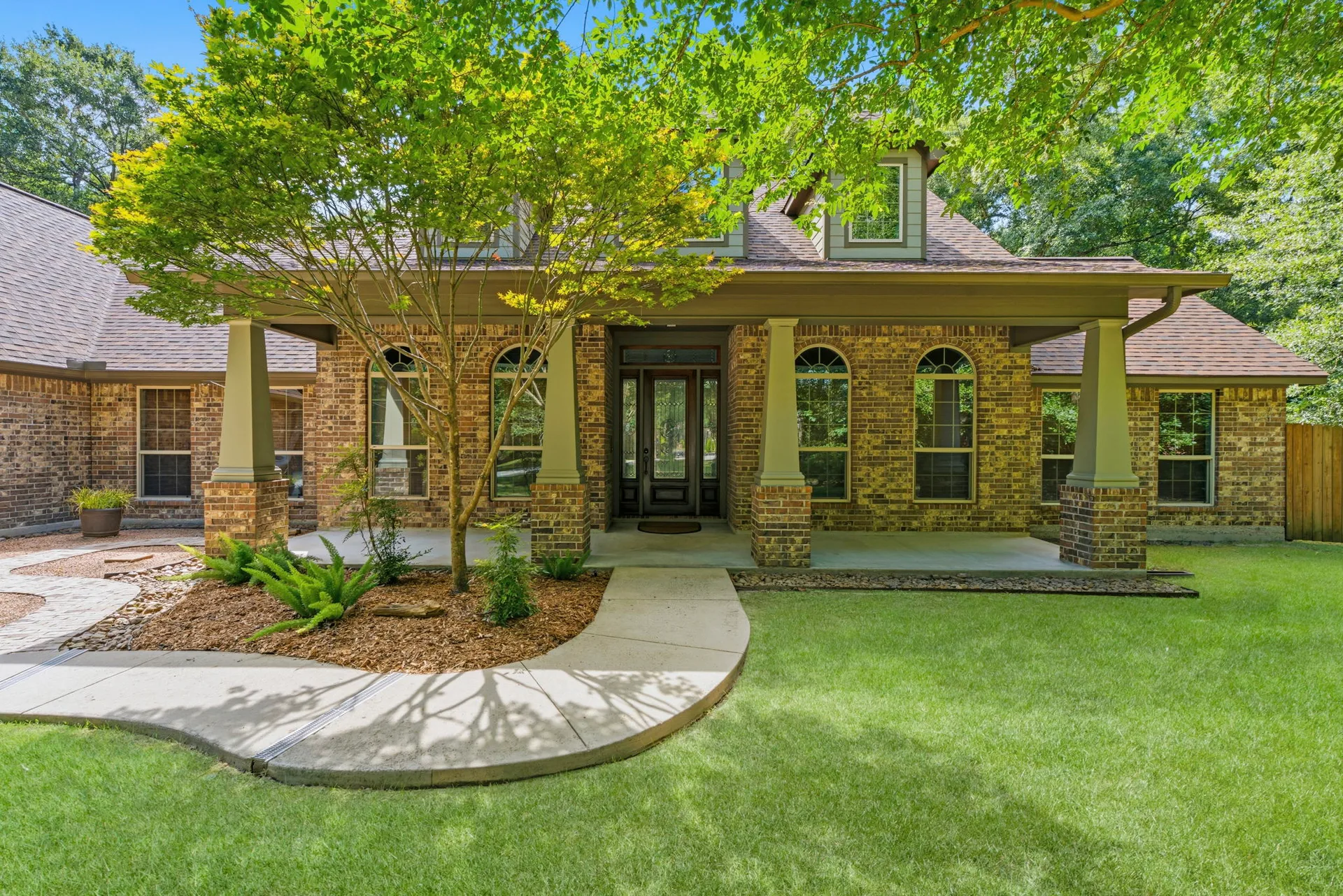 Covered front porch with stone-based columns and transom entry door
