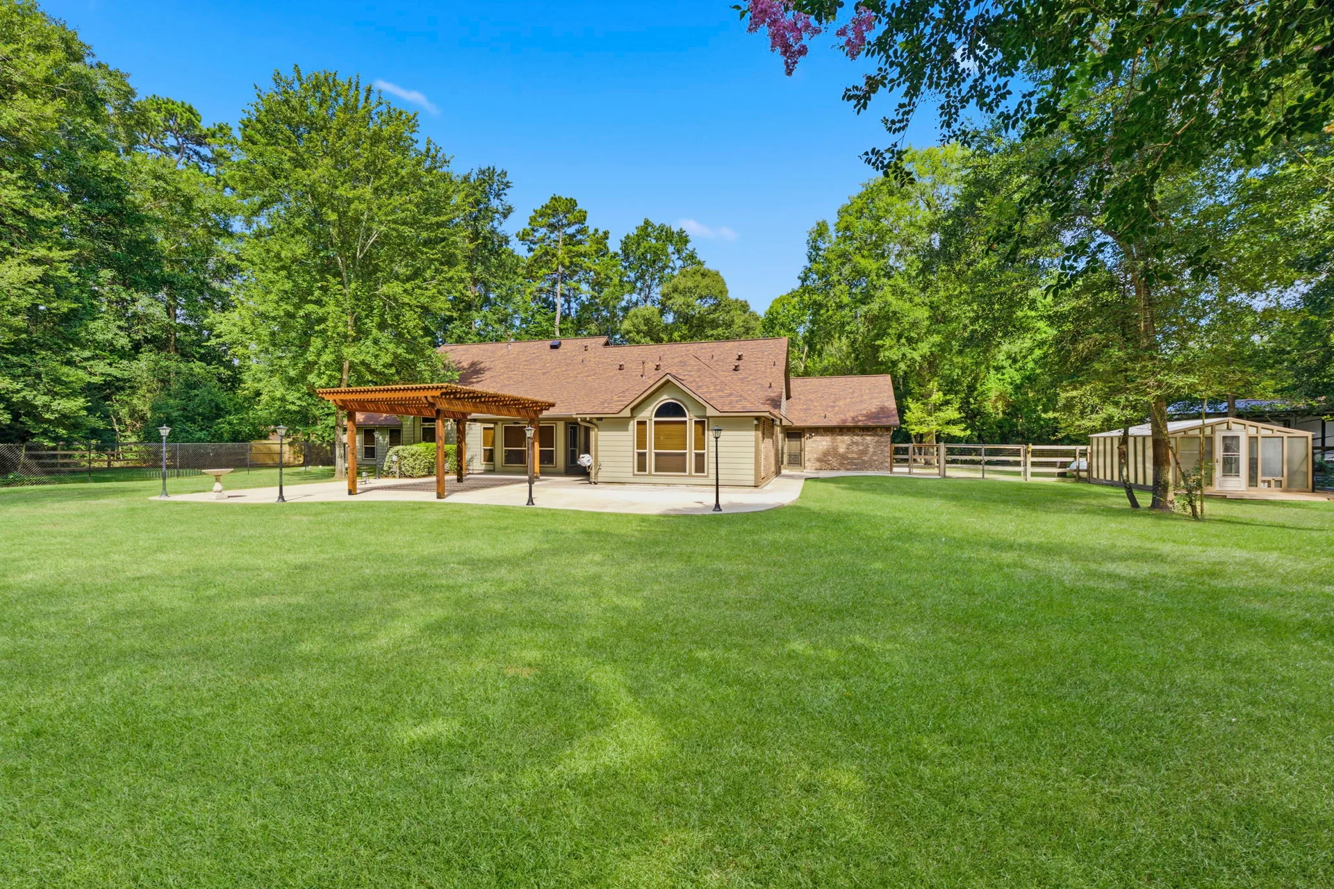 Spacious backyard with concrete patio, wooden pergola, and detached shed