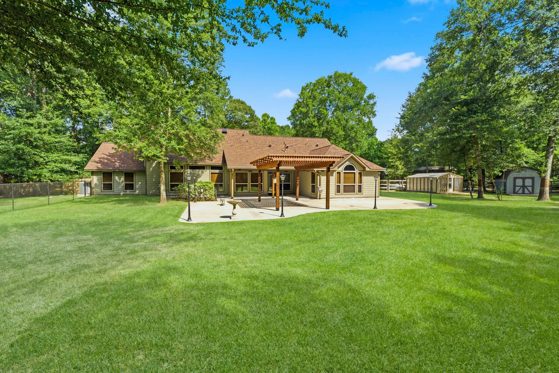 Rear of home showing covered patio with wooden pergola under blue sky