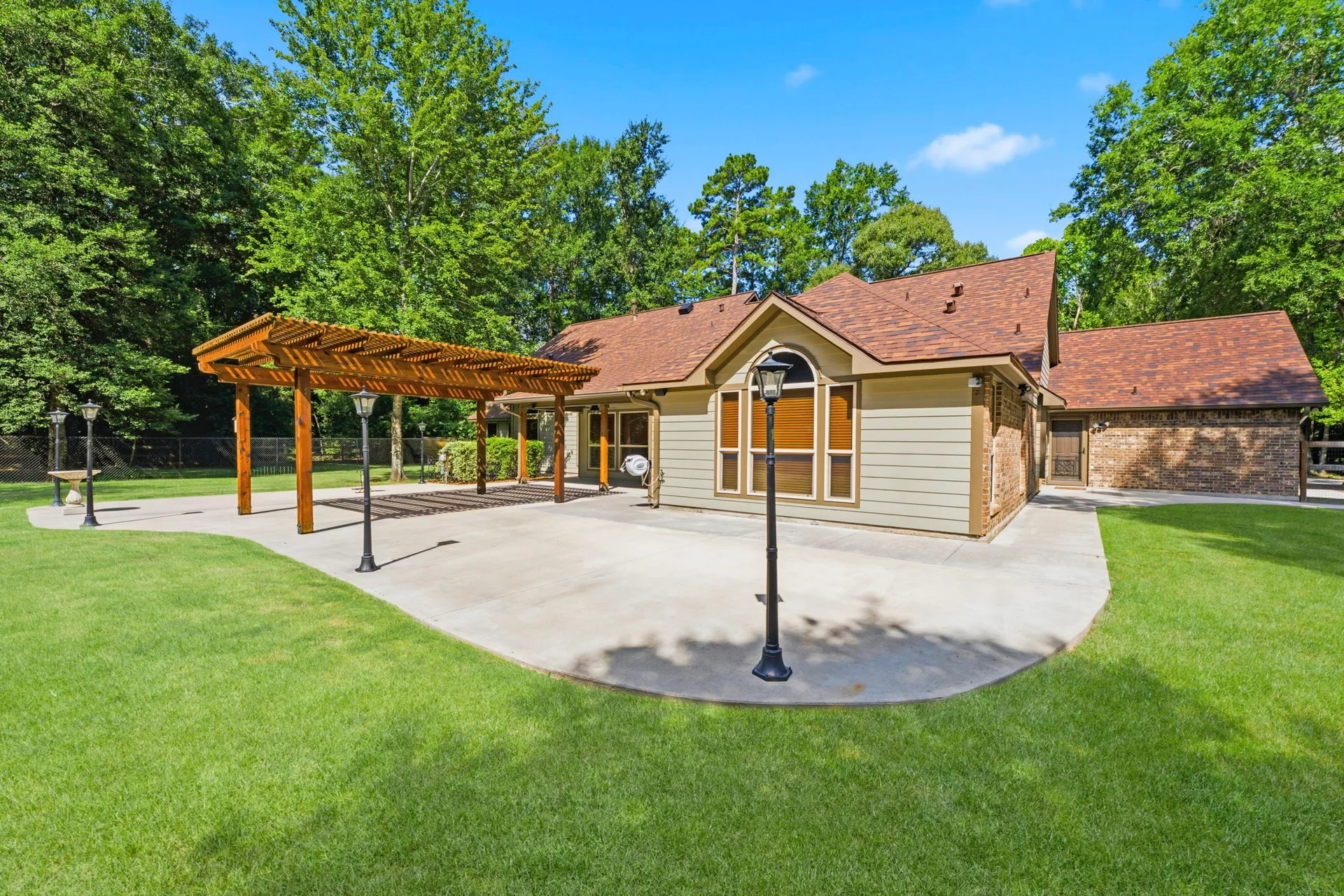 Rear facade showing cream siding, brick base, and wood pergola on patio