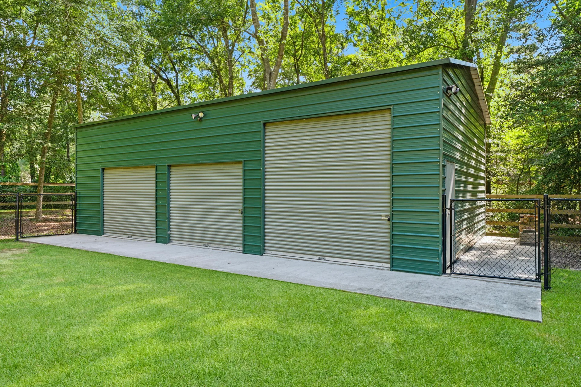 Detached metal garage with green corrugated siding and roll-up doors