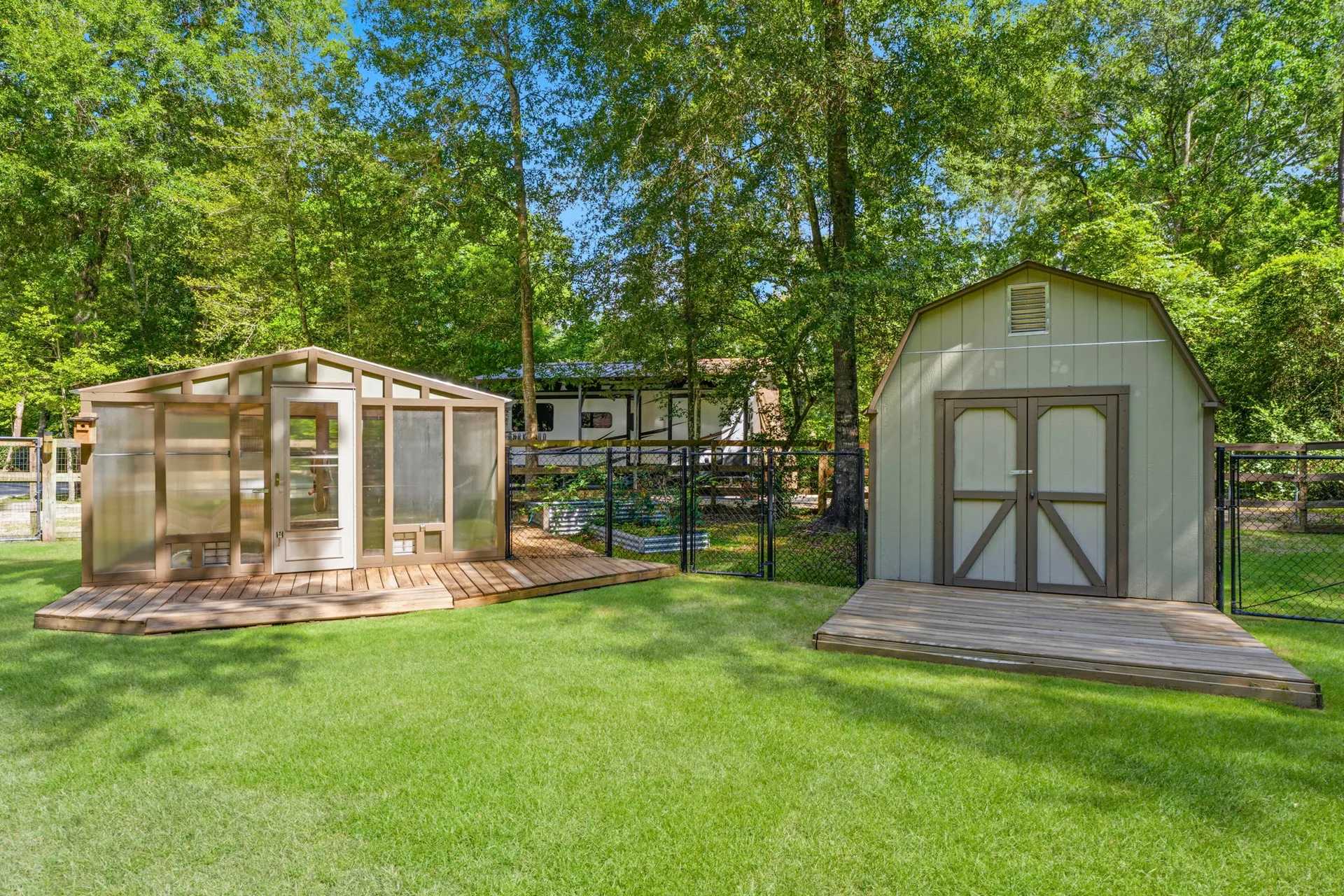 Detached greenhouse and wooden storage shed in backyard