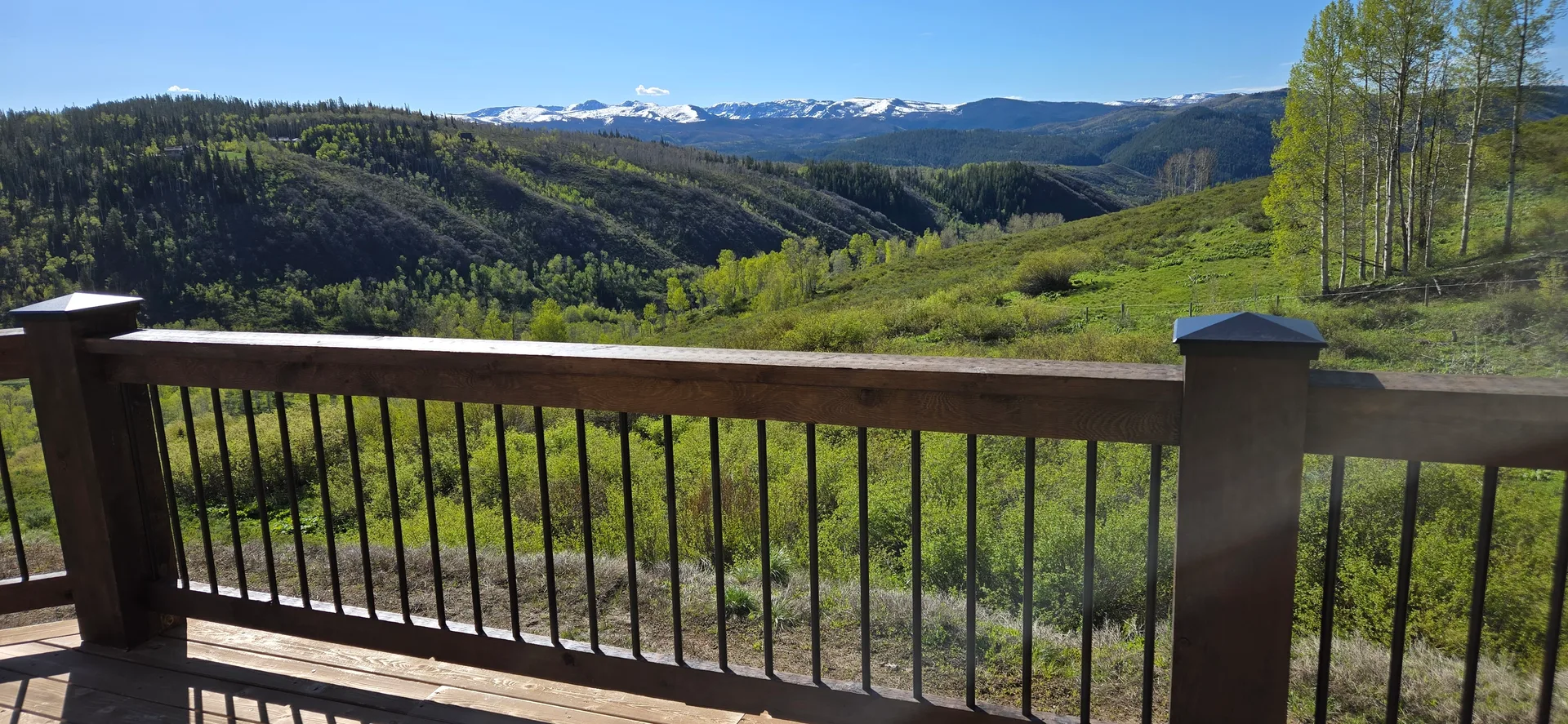 Deck view with stained wooden railing and mountain panorama