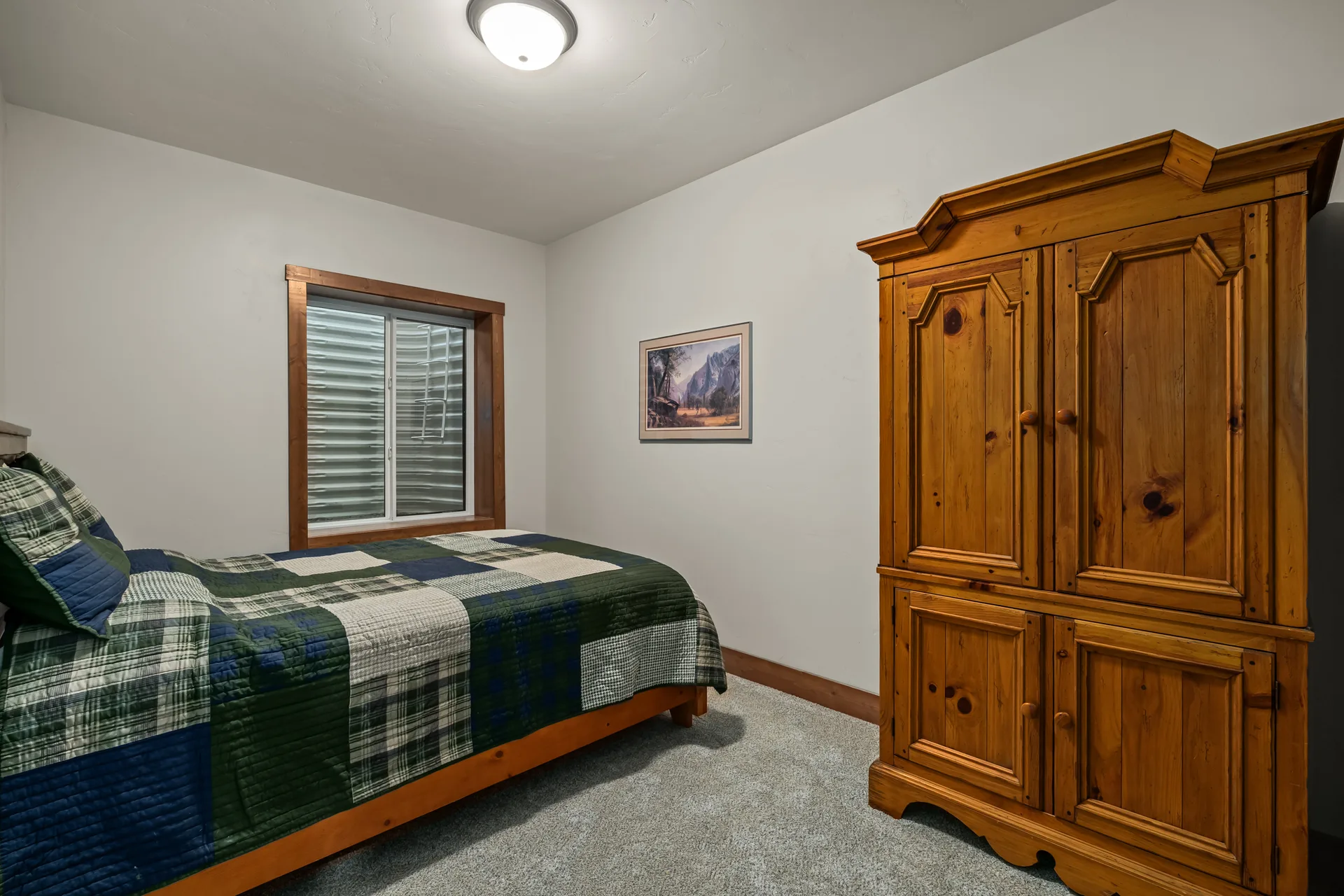 Guest bedroom with wooden armoire and patchwork quilt