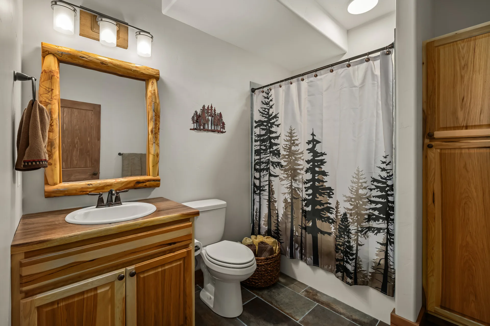 Rustic full bathroom with slate tile floor and log-framed mirror