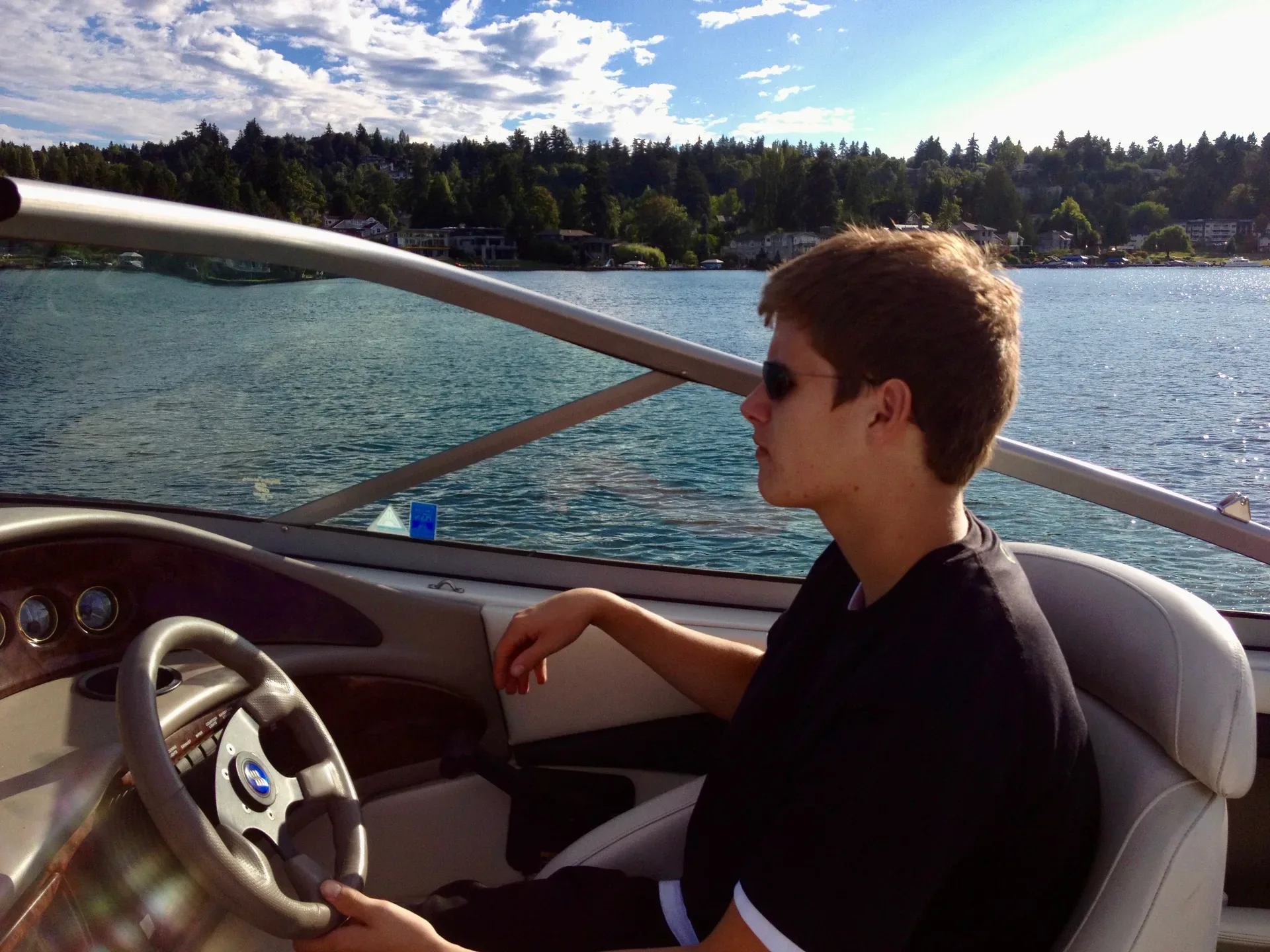 A person driving a motorboat on a sunny day on the Eastside