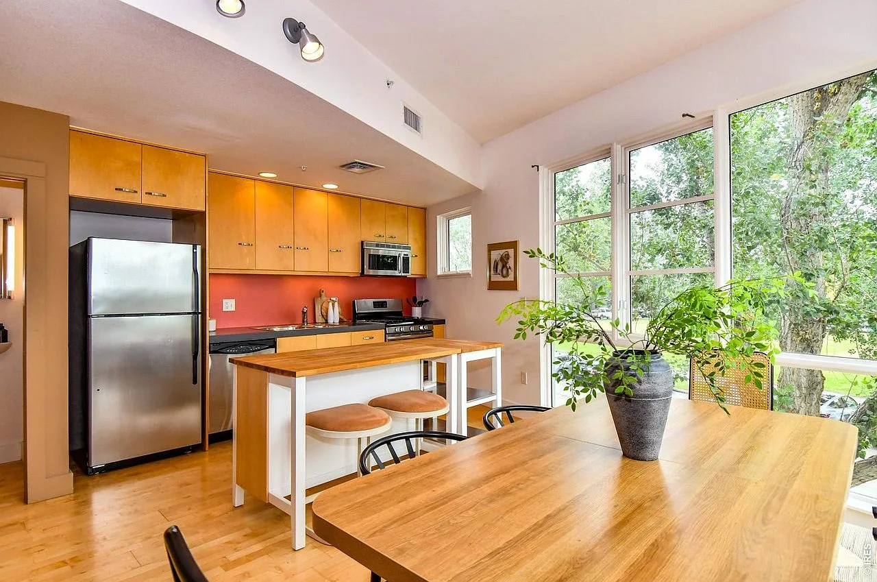 Modern kitchen with natural wood cabinetry, hardwood floors, and bright natural light