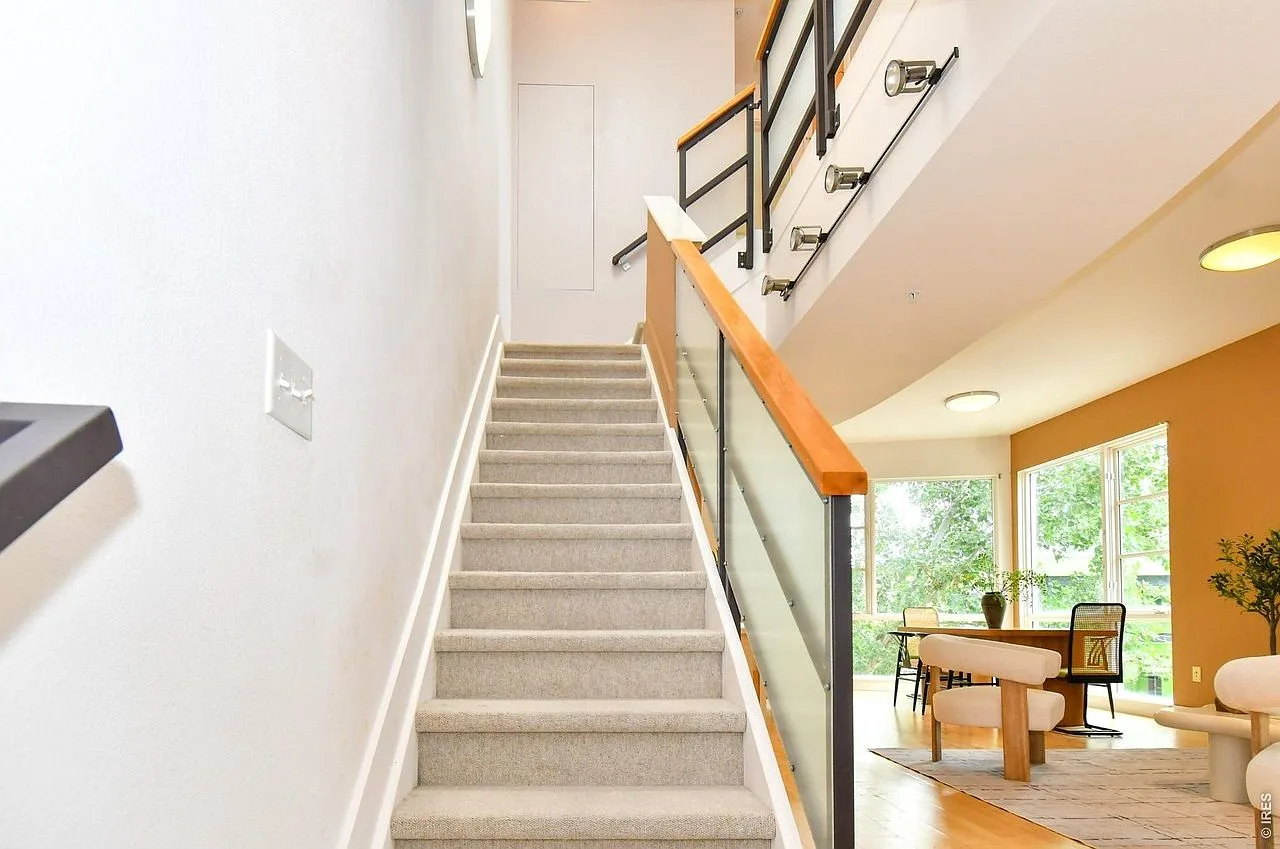 Open-concept living area showing lofted staircase and tall windows