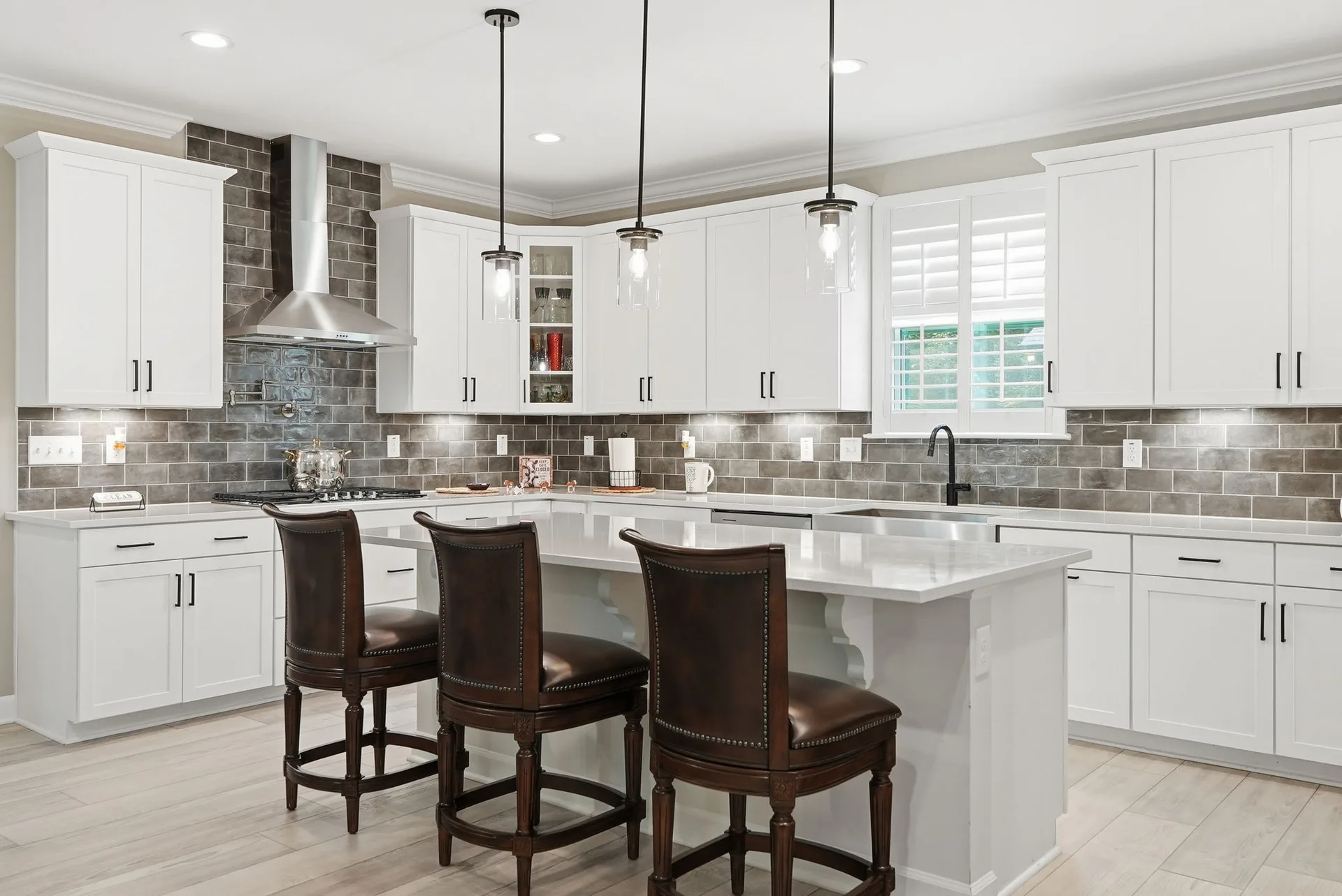 Chef's kitchen with white shaker cabinetry, stainless appliances, and quartz countertops