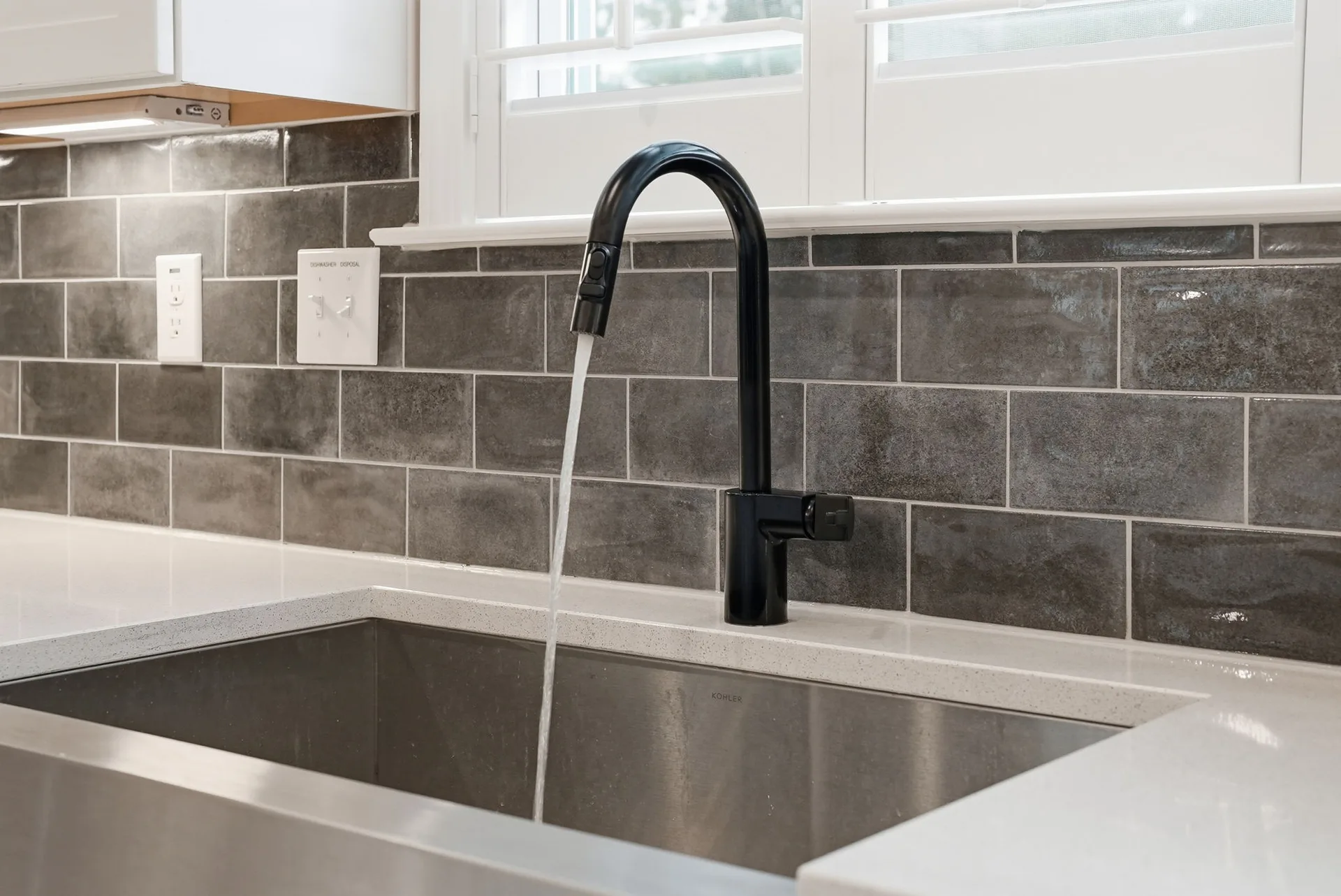 Close-up of the stainless steel farmhouse sink with matte black gooseneck faucet