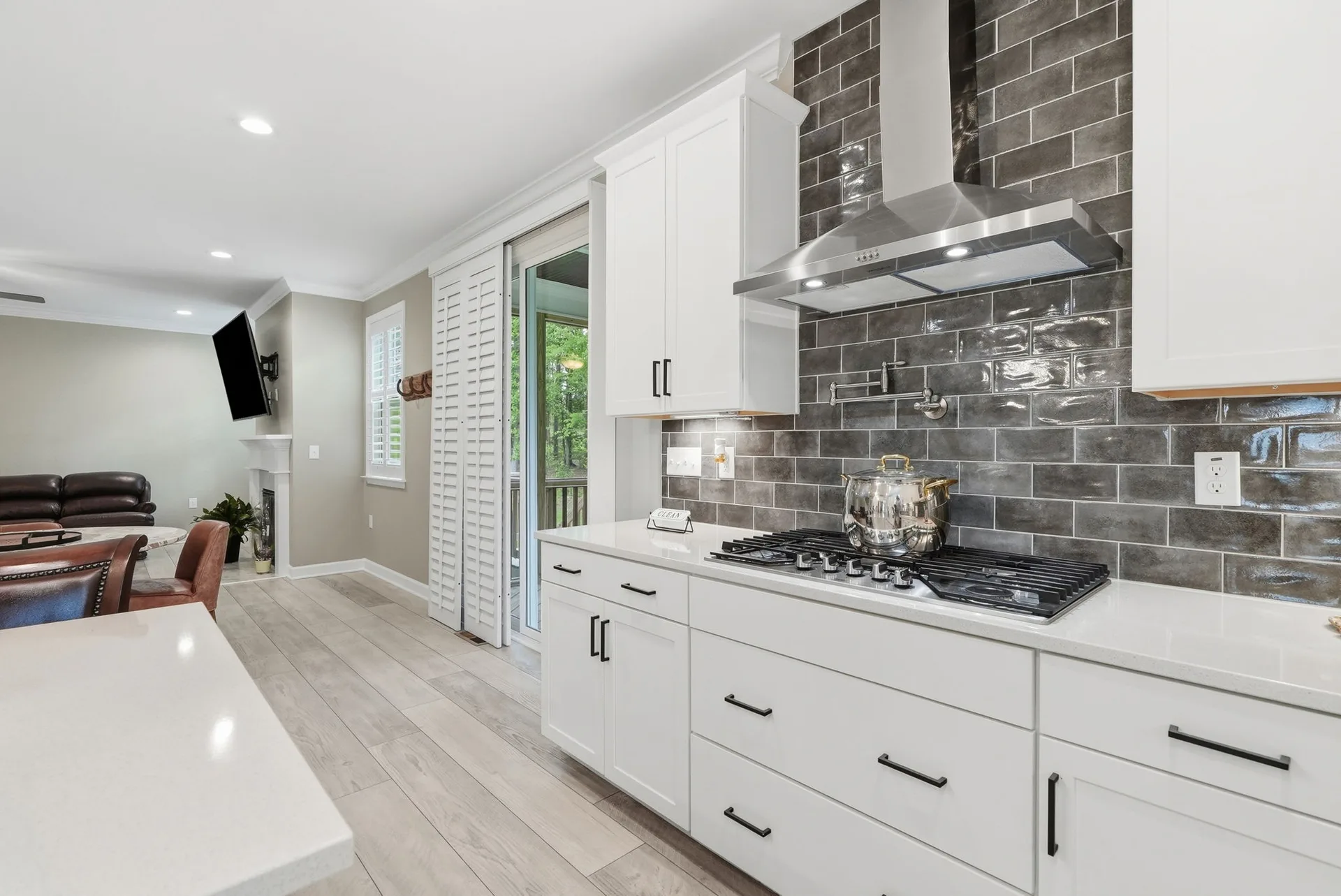 Wide shot from kitchen looking toward the living area with pot filler and stainless hood range