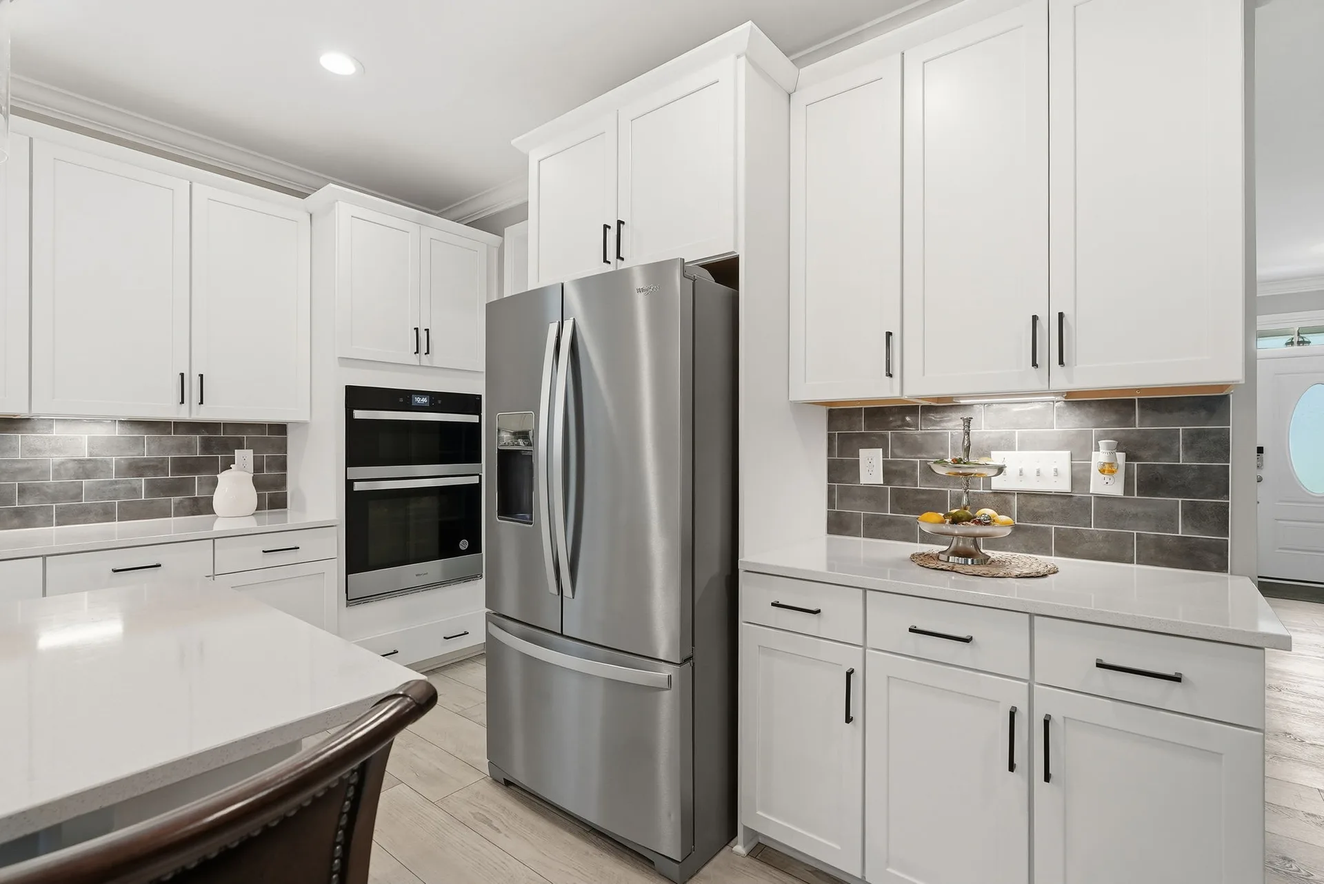 Kitchen showcasing white cabinetry with stainless steel appliances and gray subway tile backsplash
