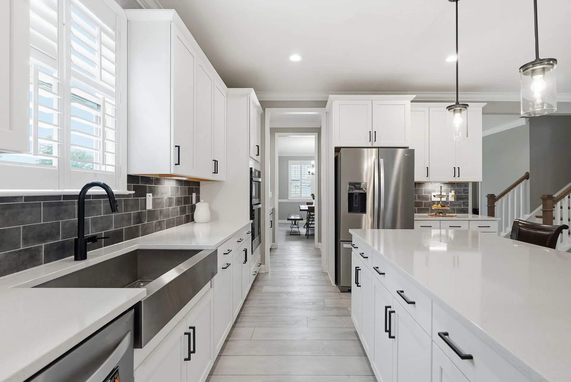 Perspective view from the sink showing white cabinetry, quartz countertops, and stainless steel appliances