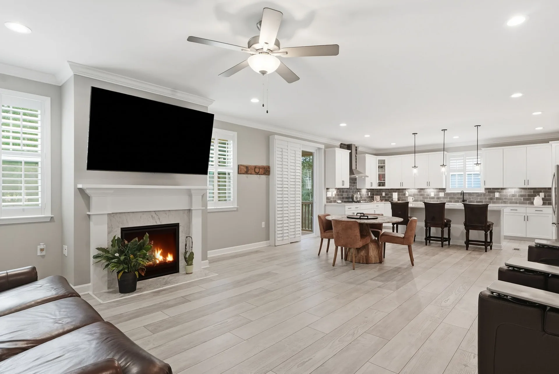 Open-concept living room transitioning to kitchen with marble-surround gas fireplace