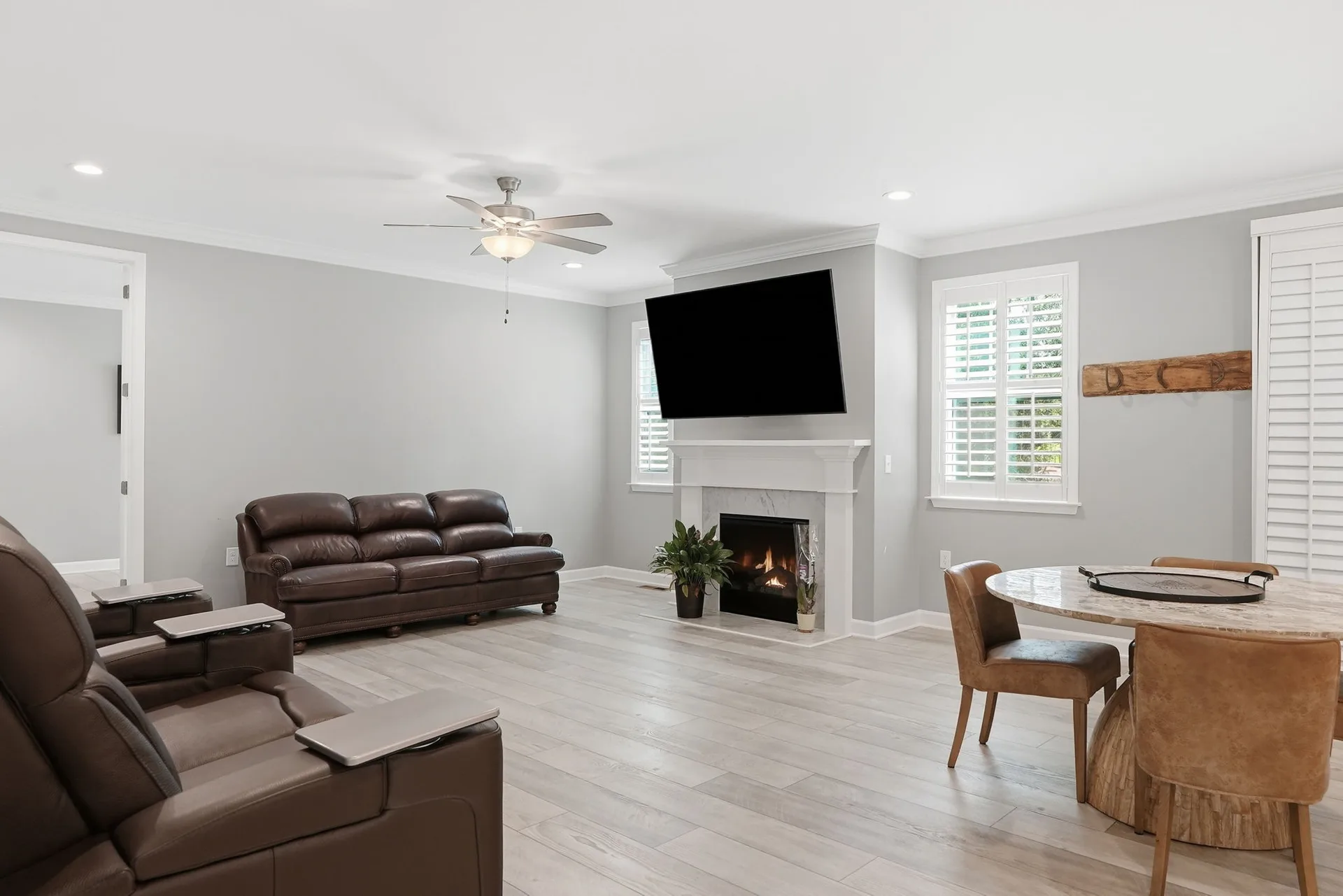 Living room with white fireplace mantle, crown molding, and plantation shutters