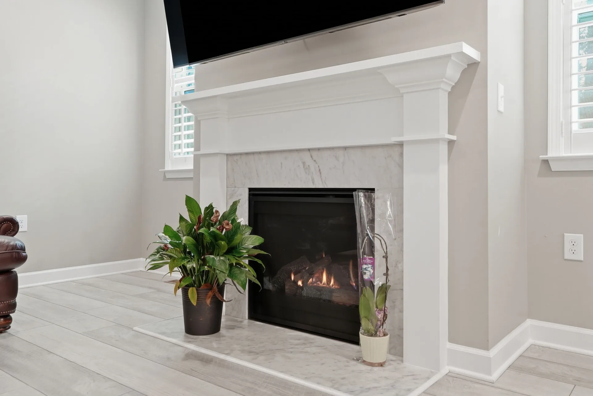 Living room detail shot focused on the white wood mantel with marble-look tile surround
