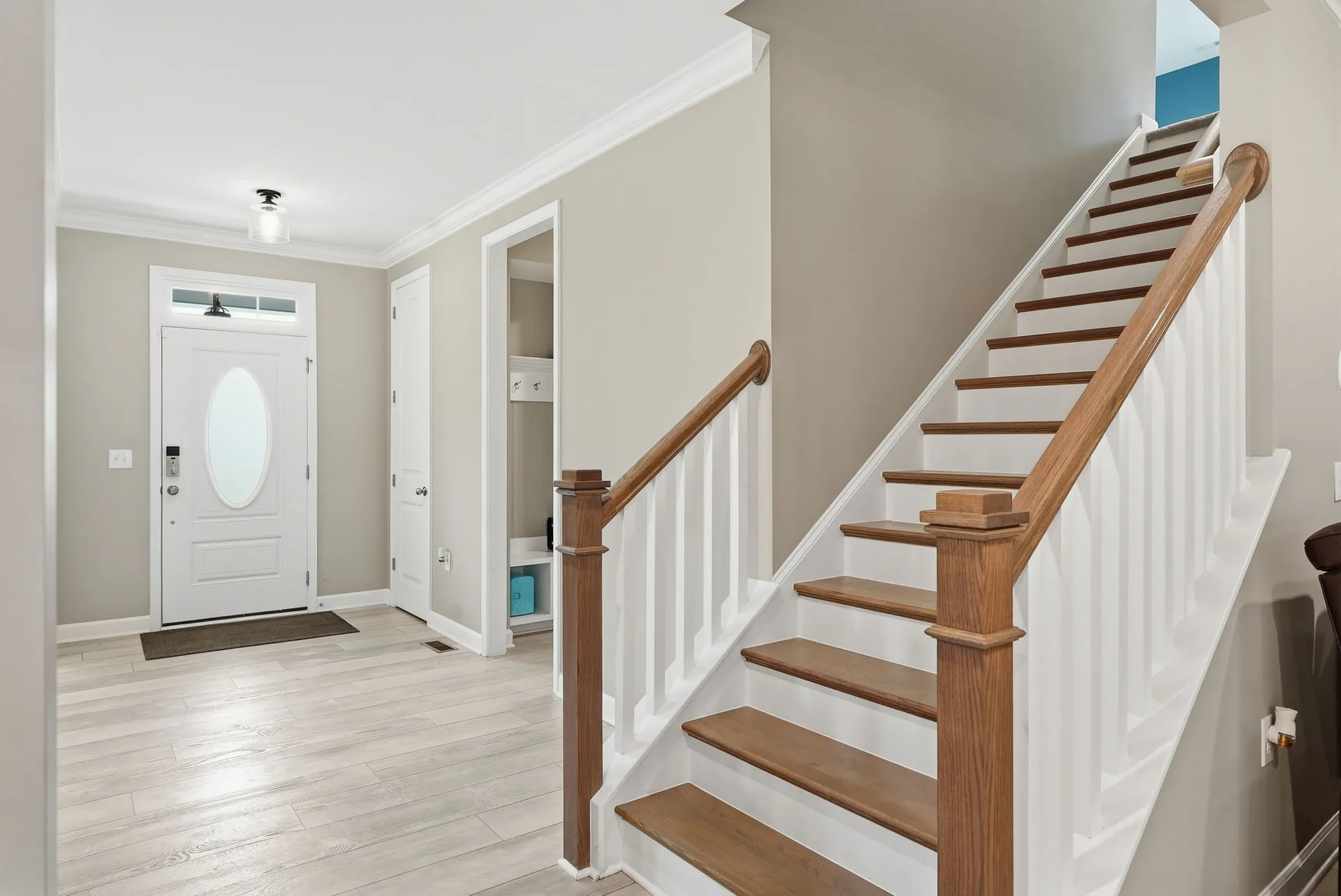 Interior foyer with light-toned wood flooring, oak stair treads, and white balusters