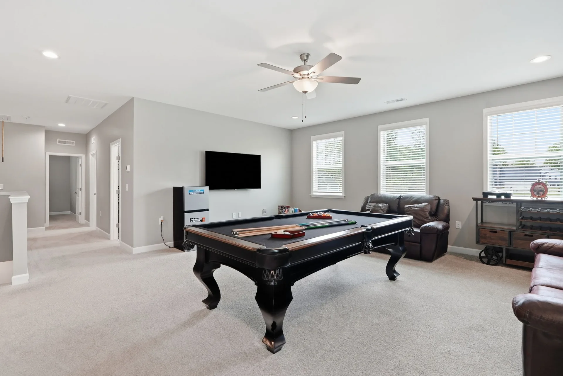 Upstairs loft and bonus room with carpet flooring, light grey walls, and natural light from windows