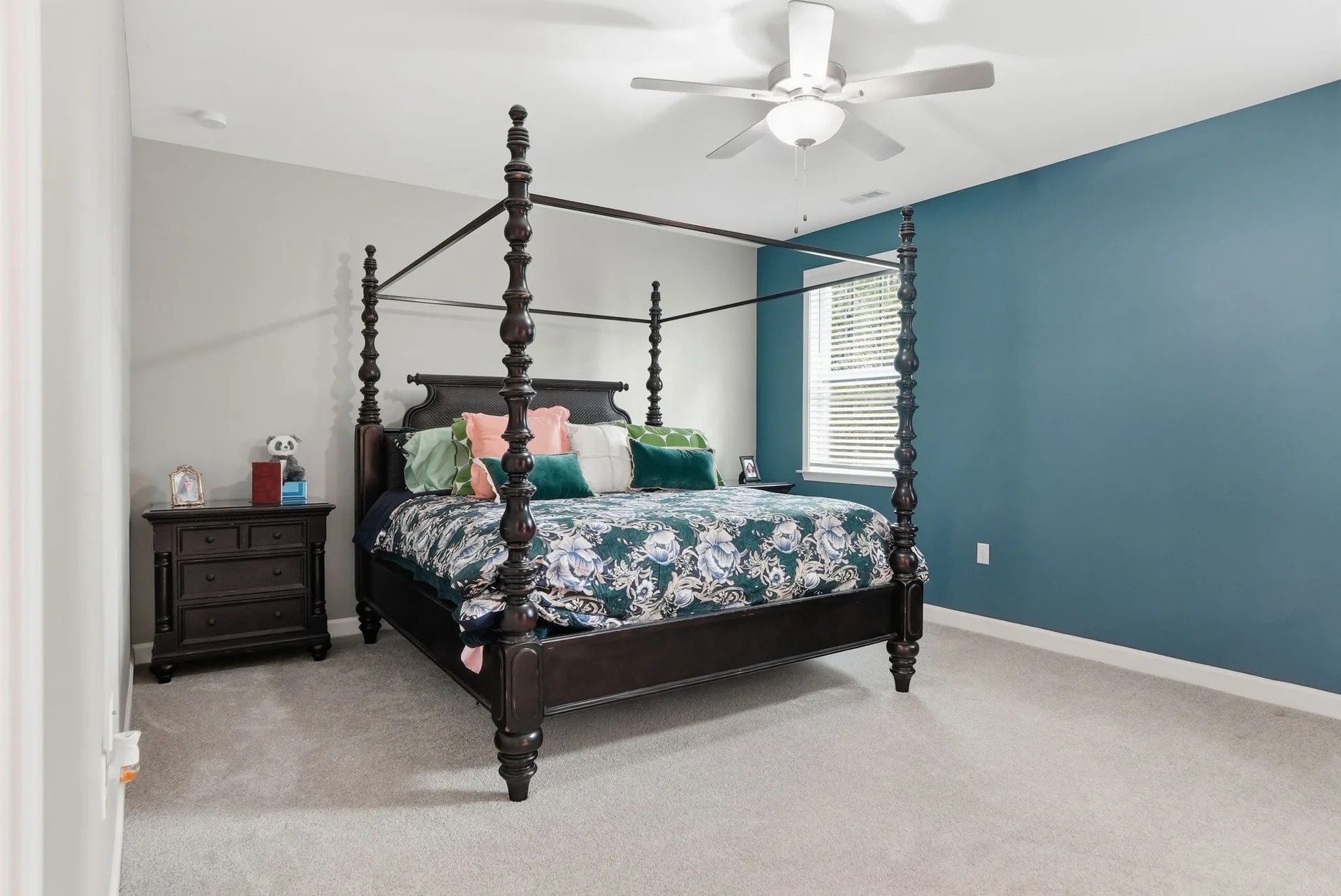 Primary bedroom with deep teal accent wall and spacious layout