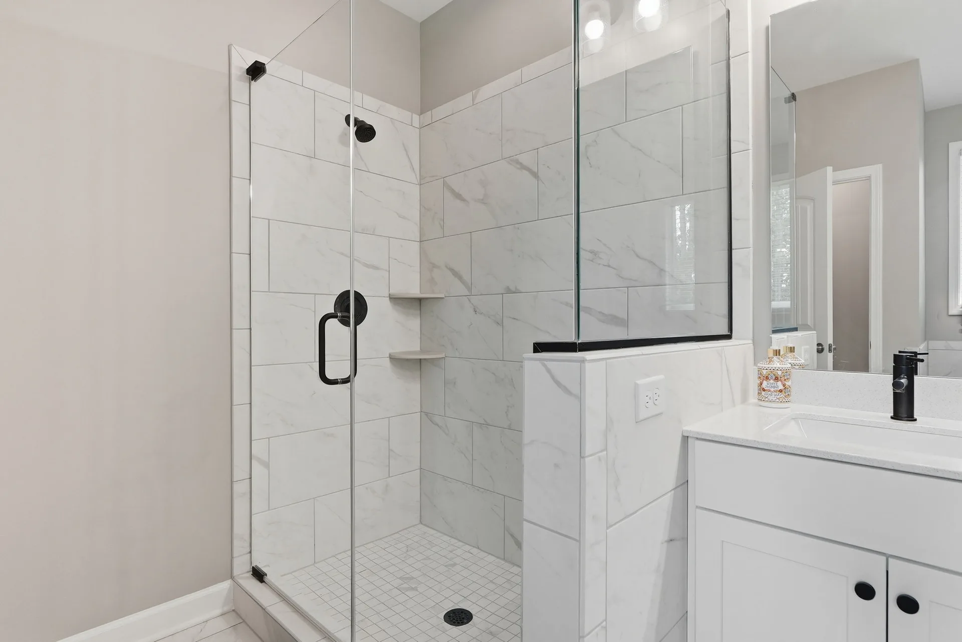 Spa-inspired master bathroom walk-in shower with marble-look tile and frameless glass