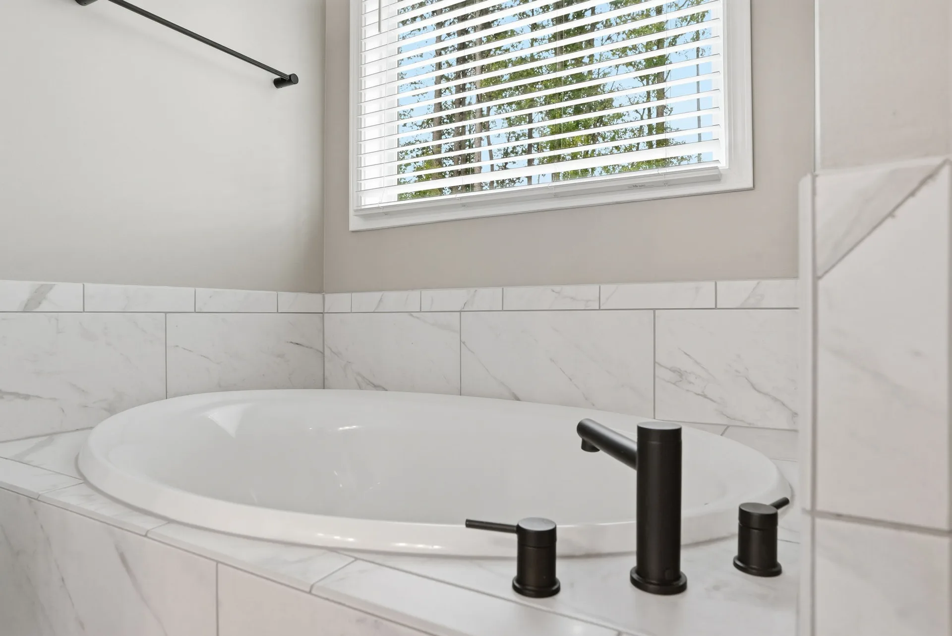 Close-up of the soaking tub with white subway-style marble-look tile surround and deck