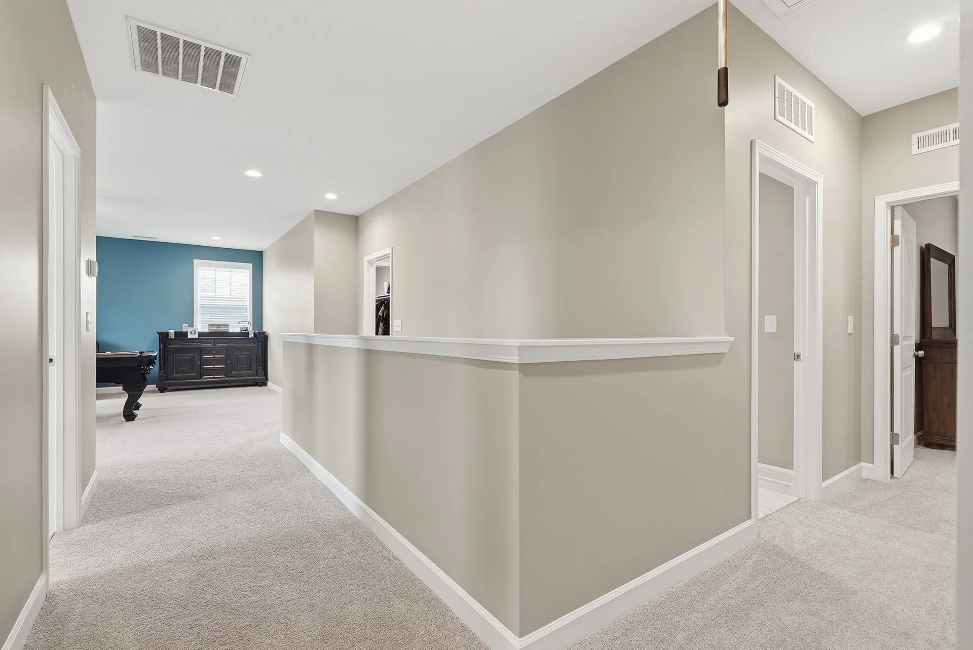 Upstairs landing and loft space with blue accent wall and carpeted floors